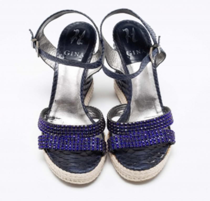 Rehaussez le charme de vos tenues avec ces magnifiques sandales Gina faciles à porter. Fabriquées en cuir de python, ces sandales sont ornées de cristaux pour un look unique. Ils sont montés sur des talons compensés