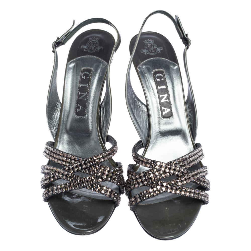 These glamorous dark grey Gina sandals look like a million bucks. Crafted in patent leather, they come embellished with crystals on the vamps. Accented with 11 cm heels, they are equipped with slingback straps with silver-tone pin