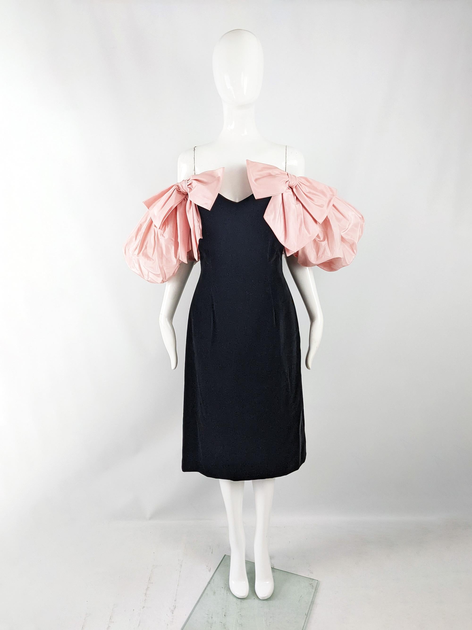 A breathtaking vintage womens evening dress from the 80s by iconic British fashion designer, Gina Fratini. In a black velvet with incredible, dramatic puffed pink silk taffeta sleeves that are off the shoulder, adorned with giant bows at the