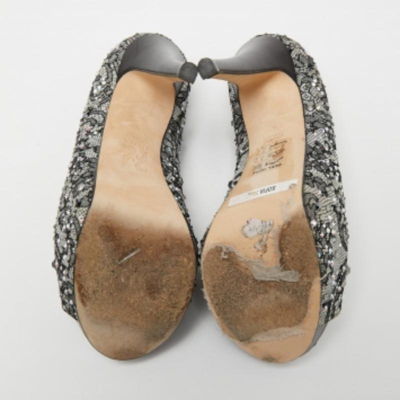 Faites chaque pas avec élégance et style grâce à ces escarpins de la maison Gina. Elles sont confectionnées avec minutie en dentelle gris-noir, rehaussée d'ornements en cristal. Ils présentent des plates-formes, des peep toes et des talons hauts.