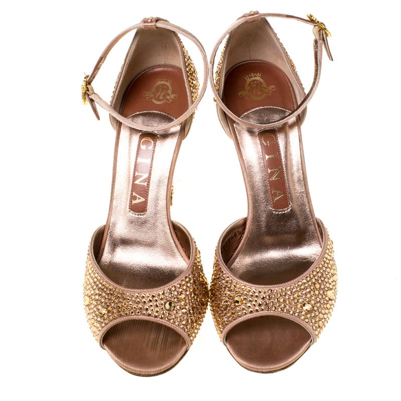 These sandals by Gina are utterly mesmerizing and filled with so much beauty, they make our hearts flutter. They carry a soul-soothing metallic bronze exterior decked with crystal embellishments and feature peep toes, ankle straps, and 10 cm heels.
