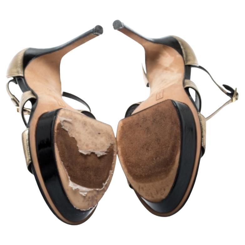 A glamorous pair from Gina, these sandals feature metallic gold uppers. Double straps at the vamp are augmented by a T-strap detail leading to the ankle straps. They are elevated by stiletto heels and platform islands on the front. A gold-tone pin