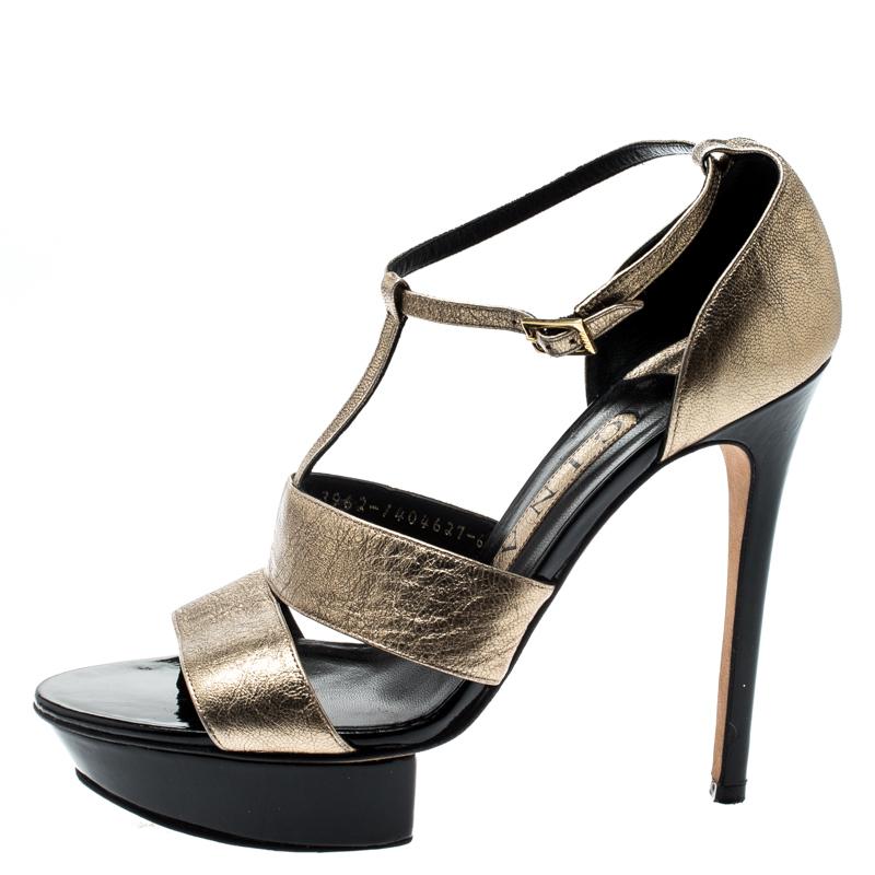 A glamorous pair from Gina, these sandals feature metallic gold uppers. Double straps at the vamp are augmented by a T-strap detail leading to the ankle straps. They are elevated by stiletto heels and platform islands on the front. A gold-tone pin