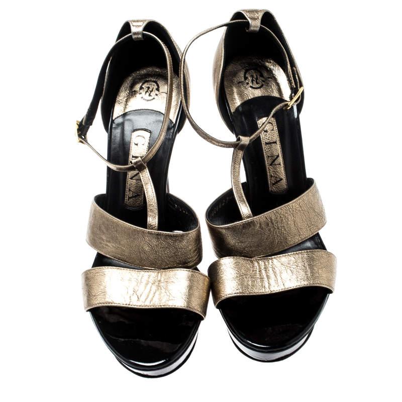 A glamorous pair from Gina, these sandals feature metallic gold uppers. Double straps at the vamp are augmented by a T-strap detail leading to the ankle straps. They are elevated by stiletto heels and platform islands on the front. A gold-tone pin