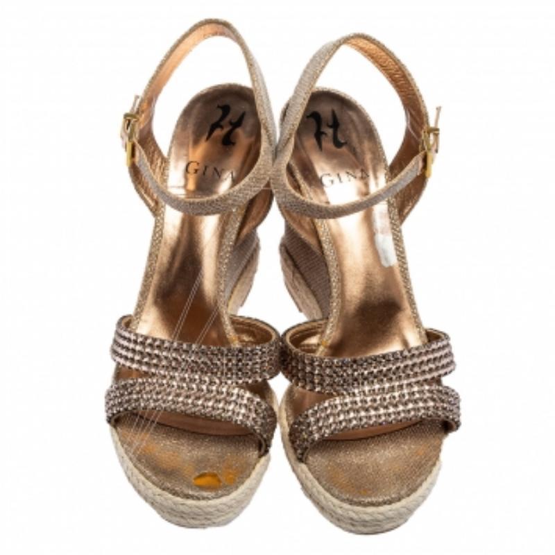 Ces sandales de la maison Gina orneront votre style en un rien de temps ! Elles sont réalisées en cuir pailleté or rose et orné de cristaux sur l'extérieur, dotées de semelles compensées et de ferrures dorées. Possédez ces sandales Gina dès