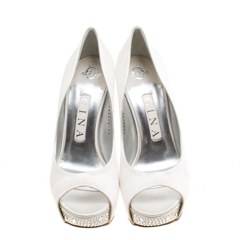 Adorn your feet with this adorable pair of platform pumps by Gina. Boasting a white satin exterior, they feature beautiful crystal embellishments on the high stiletto heels and platforms. The insoles are leather-lined and carry brand detailing.