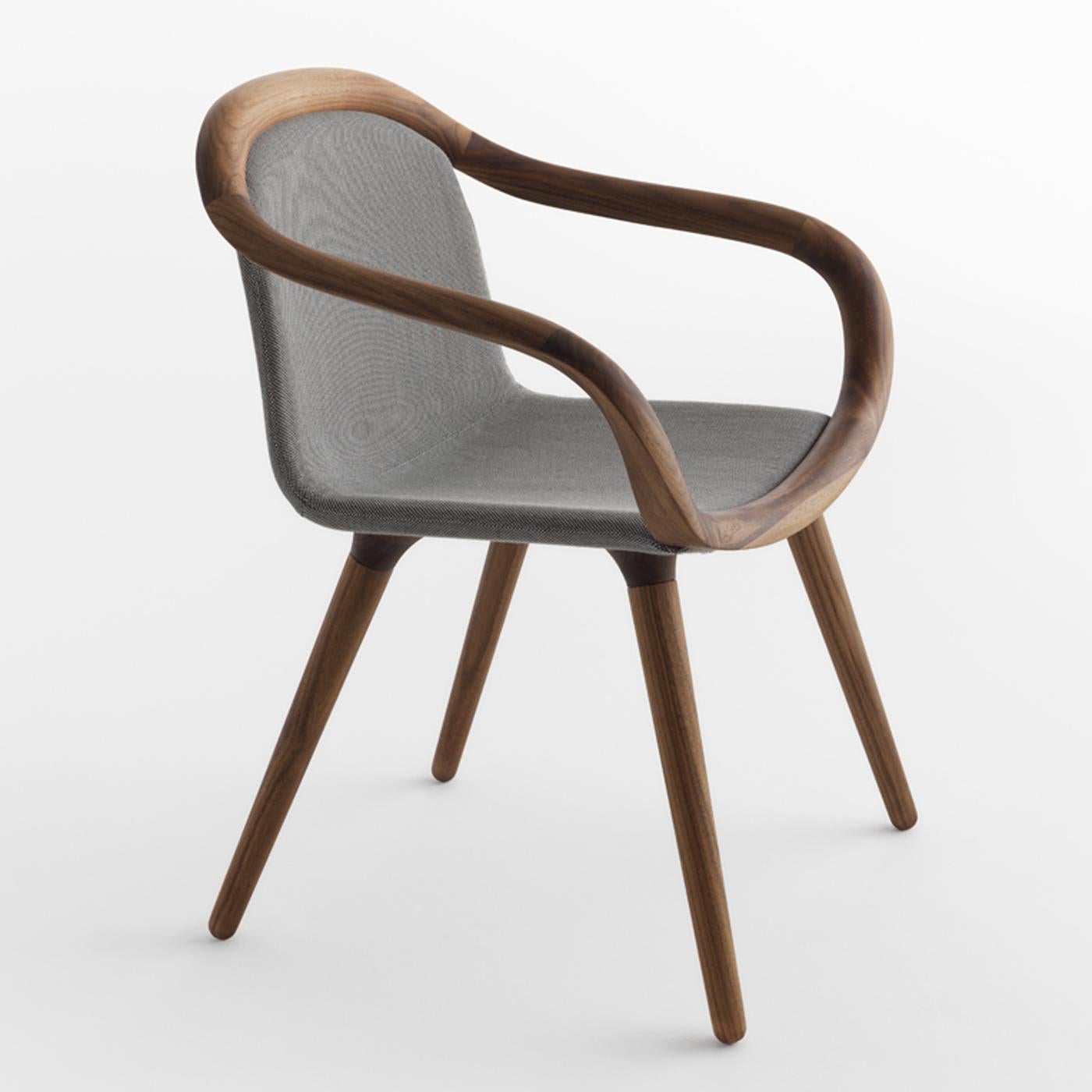 Sinuous and gentle lines depict the silhouette of this exquisite chair, exuding comfort and elegance. Resting on a solid walnut wood structure with slanted legs and wavy armrests, it features seat and backrests upholstered in light blue fabric (also