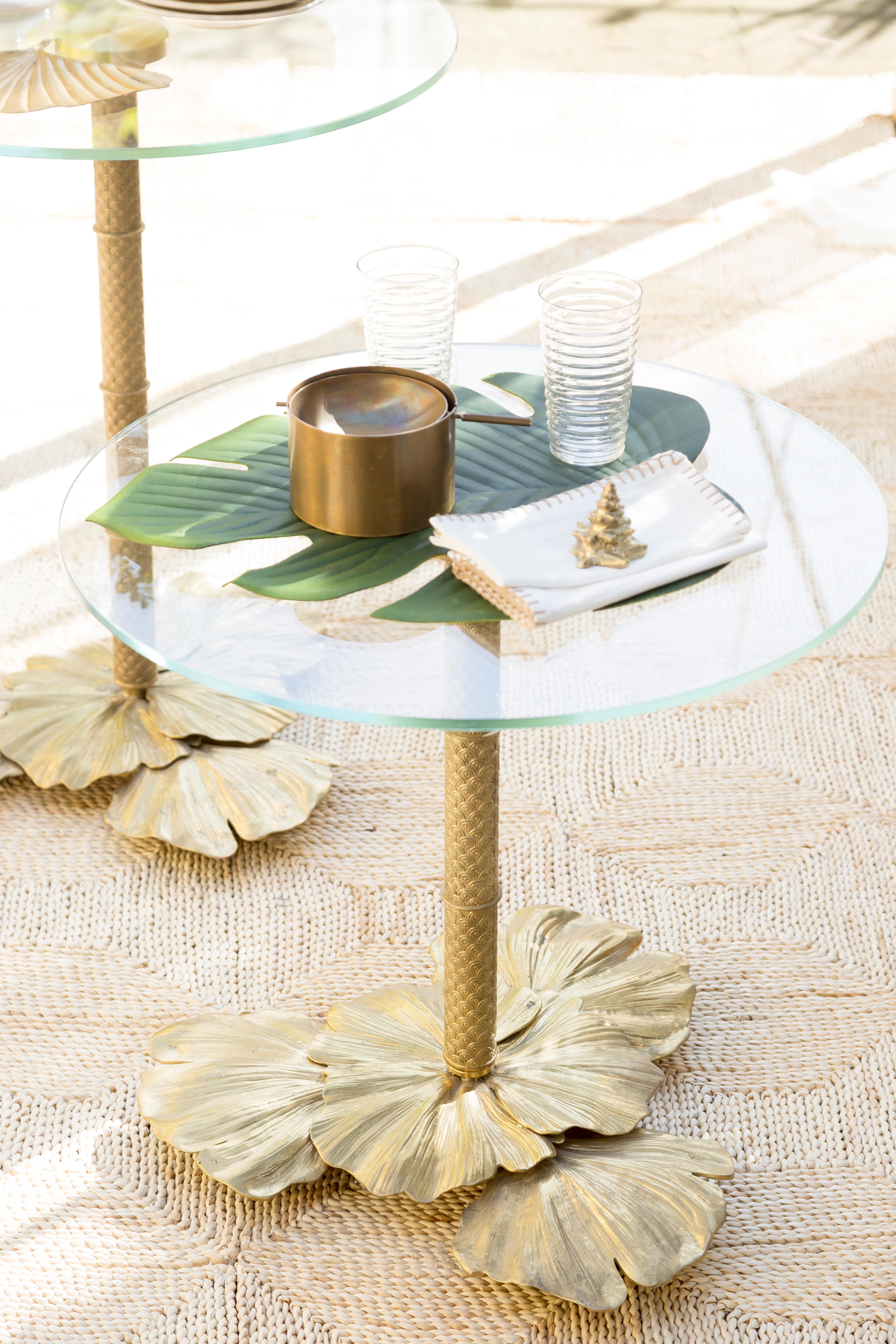 The Ginkgo 01 bistrot table has a brass structure in natural brass finish and a clear glass top, it pertains to the Eclectic collection by Bronzetto where each piece is crafted to create irregular and rought surfaces with uneven finishes which best