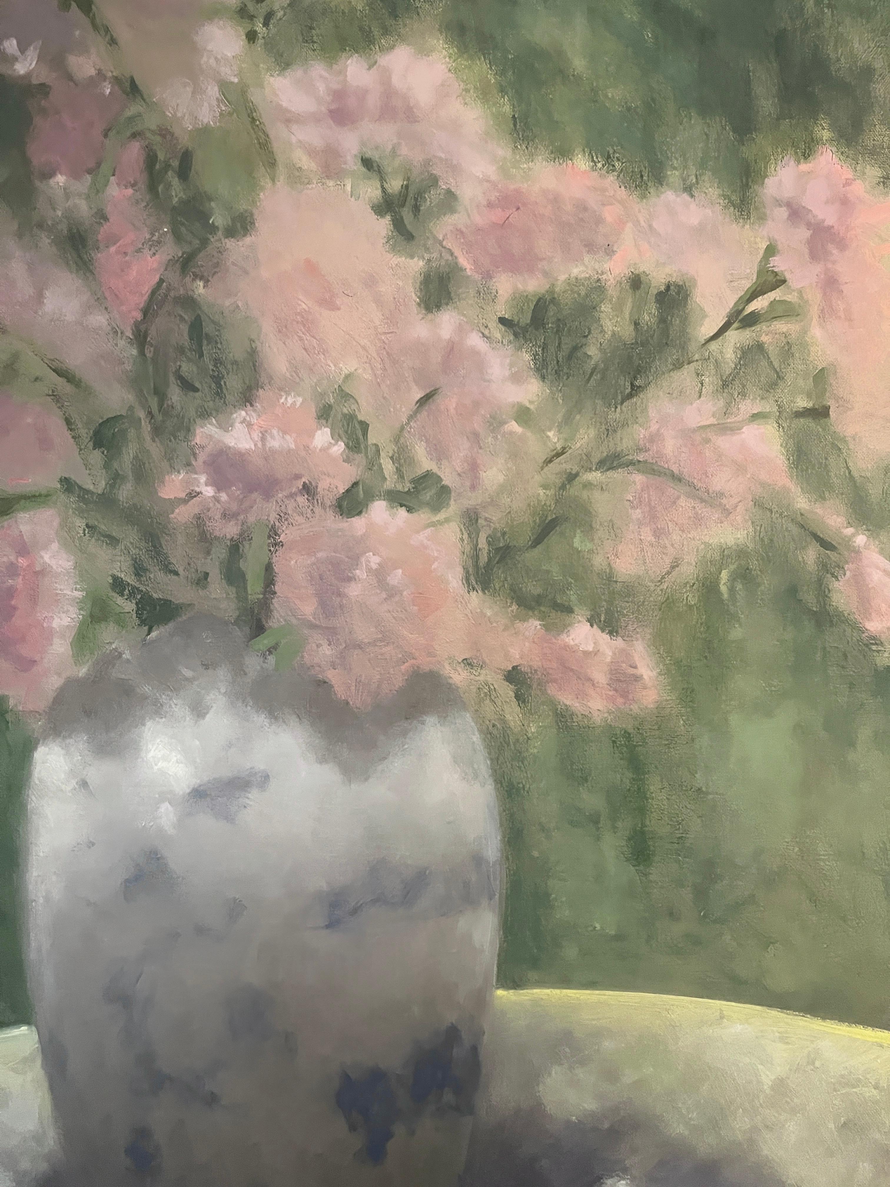 Questo pezzo è un dipinto a olio originale su tela di lino. Presenta un vaso di porcellana blu e bianco della collezione dell'artista con garofani rosa appoggiati su un tavolo. La luce del sole, a cui fa riferimento il titolo dell'opera, filtra