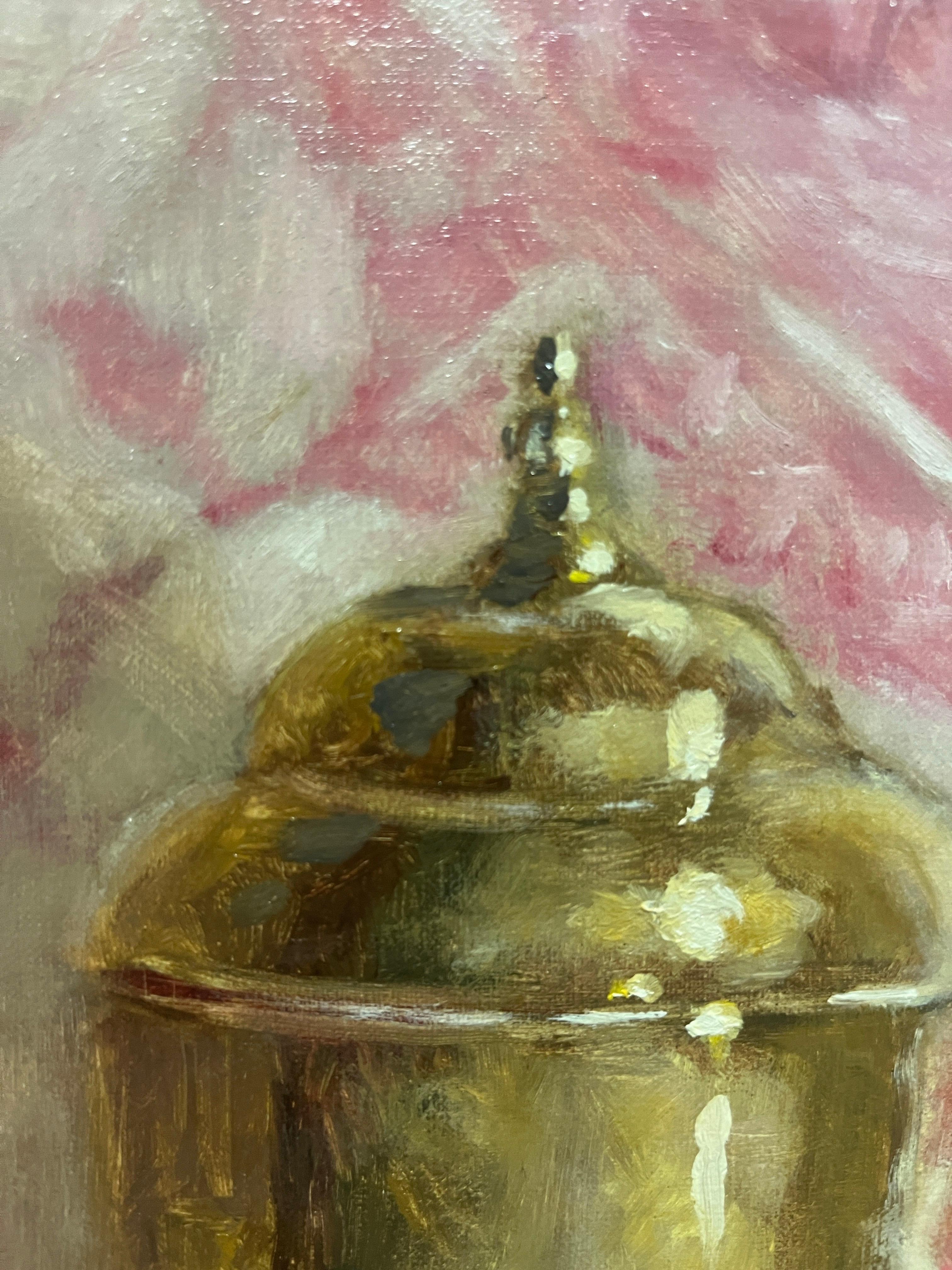 Questo pezzo è un dipinto a olio originale su pannello. Presenta un vaso d'oro seduto su un panno rosso e bianco dai colori intensi. Incorniciato in una cornice in stile pendio con un bordo interno dorato che si abbina all'oro dell'opera. I lati