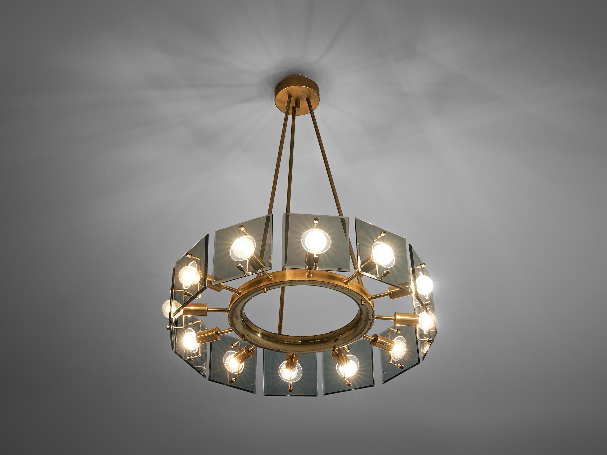 Gino Paroldo, chandelier, glass, metal, brass, Italy, 1960s

Stunning round chandelier in glass, metal and brass designed by Gino Paroldo. A round center holds twelve light bulbs behind tempered squared glass plates. The circle is held by three thin