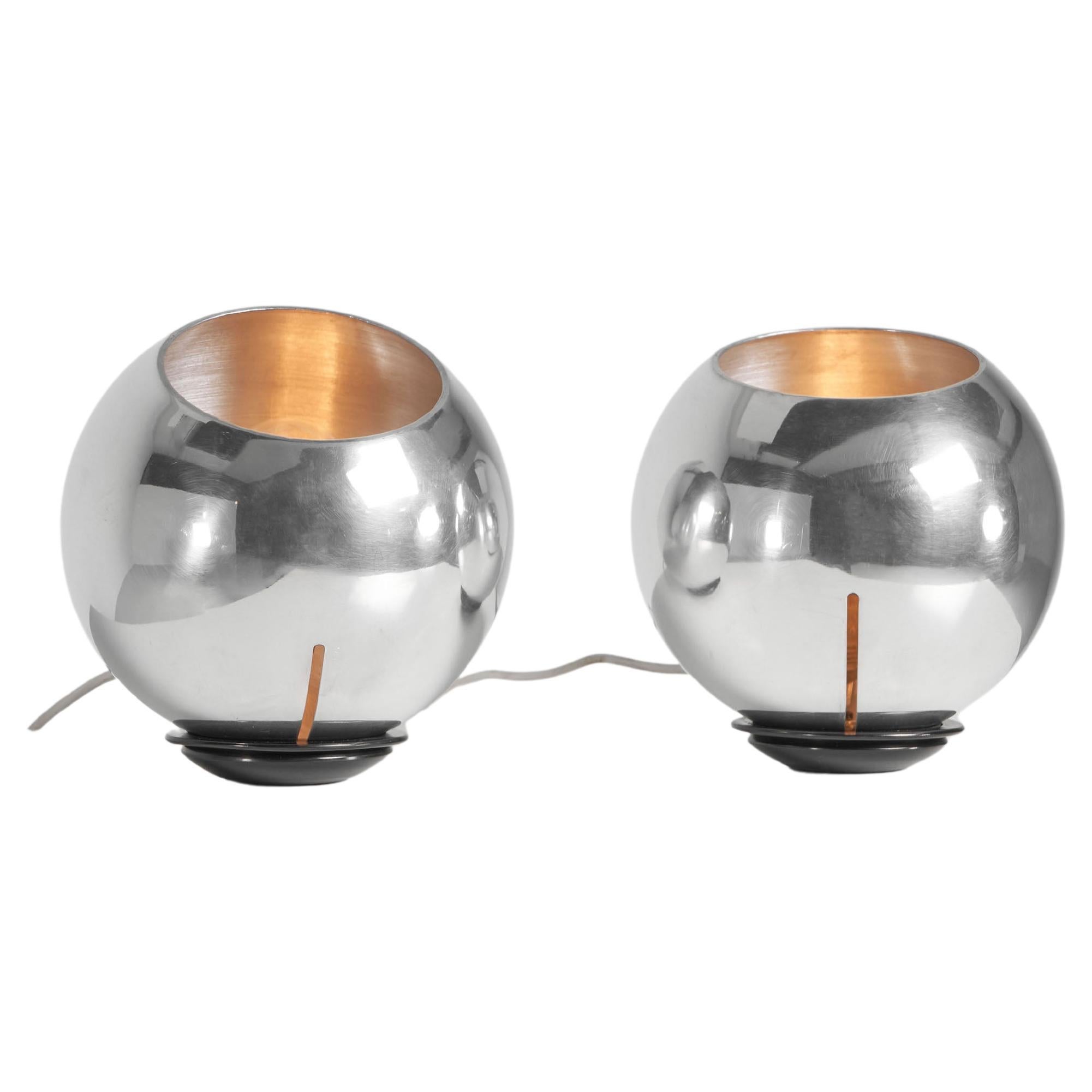 Nice playful pair of adjustable table lamps designed by Gino Sarfatti and manufactured by Arteluce, Italy 1962. Sheared off sphere-shaped reflector in polished aluminium simply supported on an iron weighted base in painted finish black. Round