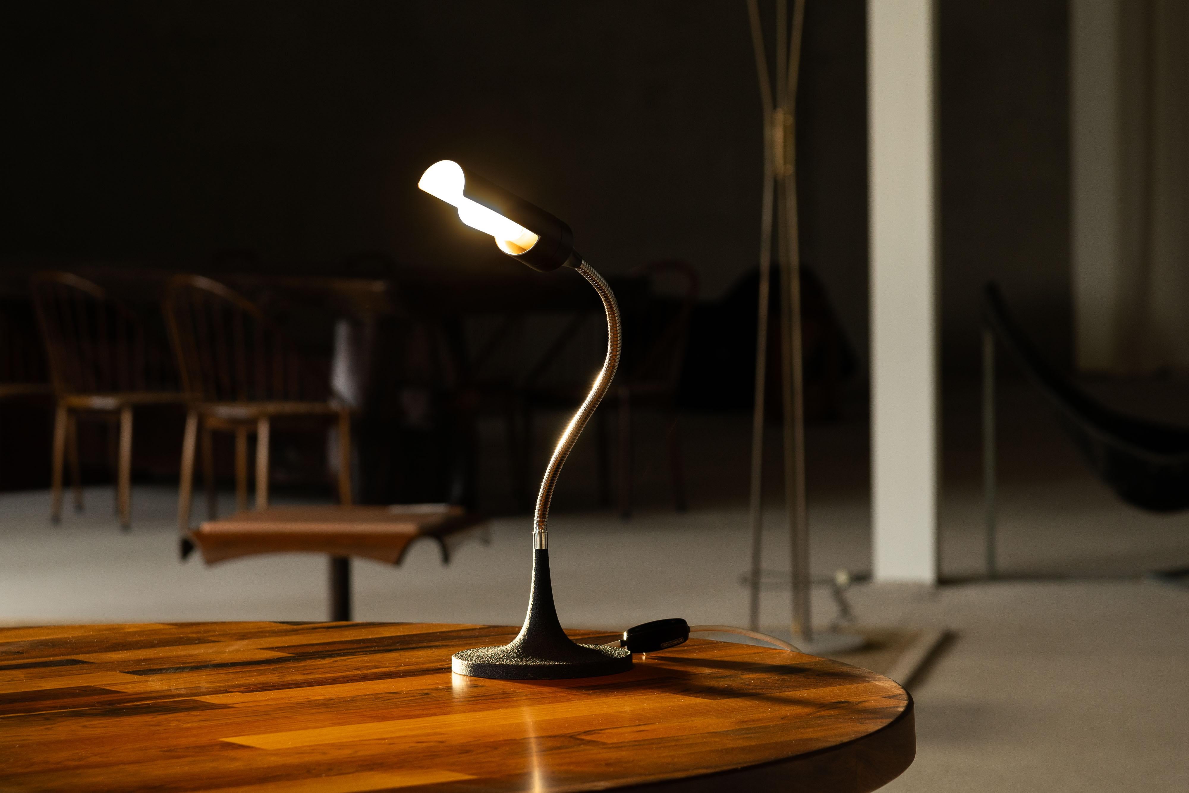 The Sculptural and Adjustable Table Lamp Model 595, designed by Gino Sarfatti and manufactured by Arteluce in Italy in 1961, is an iconic piece that showcases mid-century modern lighting design. This elegant lamp features a black-painted aluminum