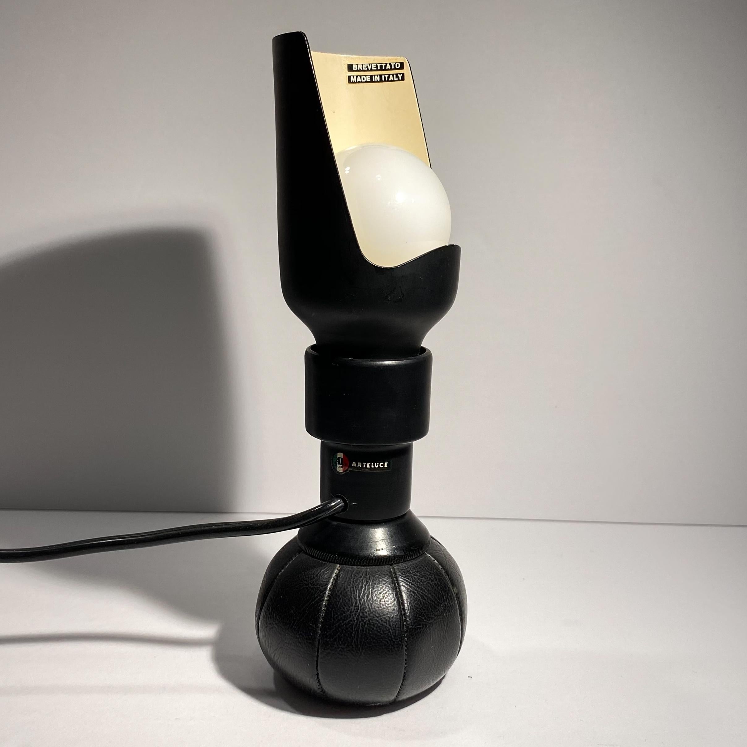 Table lamp model 600P by renowned Italian lighting designer Gino Sarfatti, produced by Arteluce, circa 1966. An early example with the cut-out lacquered aluminum diffuser. The lamp rests atop a leather pouch filled with lead pellets, allowing for