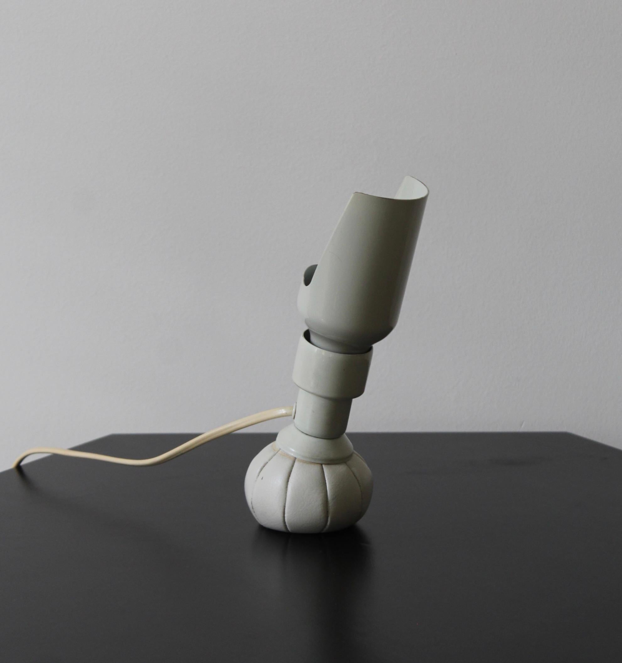 An adjustable table lamp, designed and produced by Gino Sarfatti for Arteluce, Italy, 1966.

White-lacquered metal socket is mounted on the base in form of a leather pouch filled with sand.
