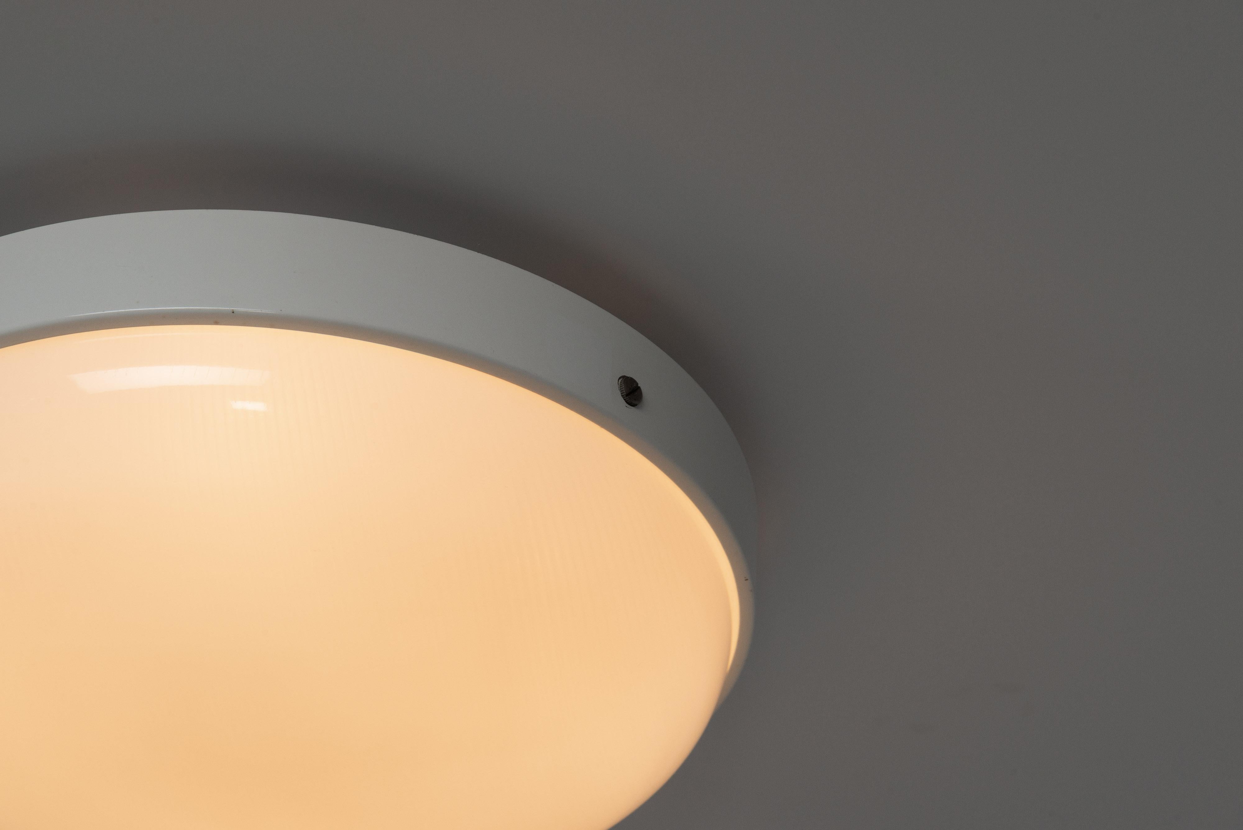 Modernist Model 3001/40 ceiling lamps designed by Gino Sarfatti and manufactured by Arteluce in Italy in 1950. Nice minimal design with the rounded shape and the plexiglass shade that is slightly curved. The shade is held by screws on the side of