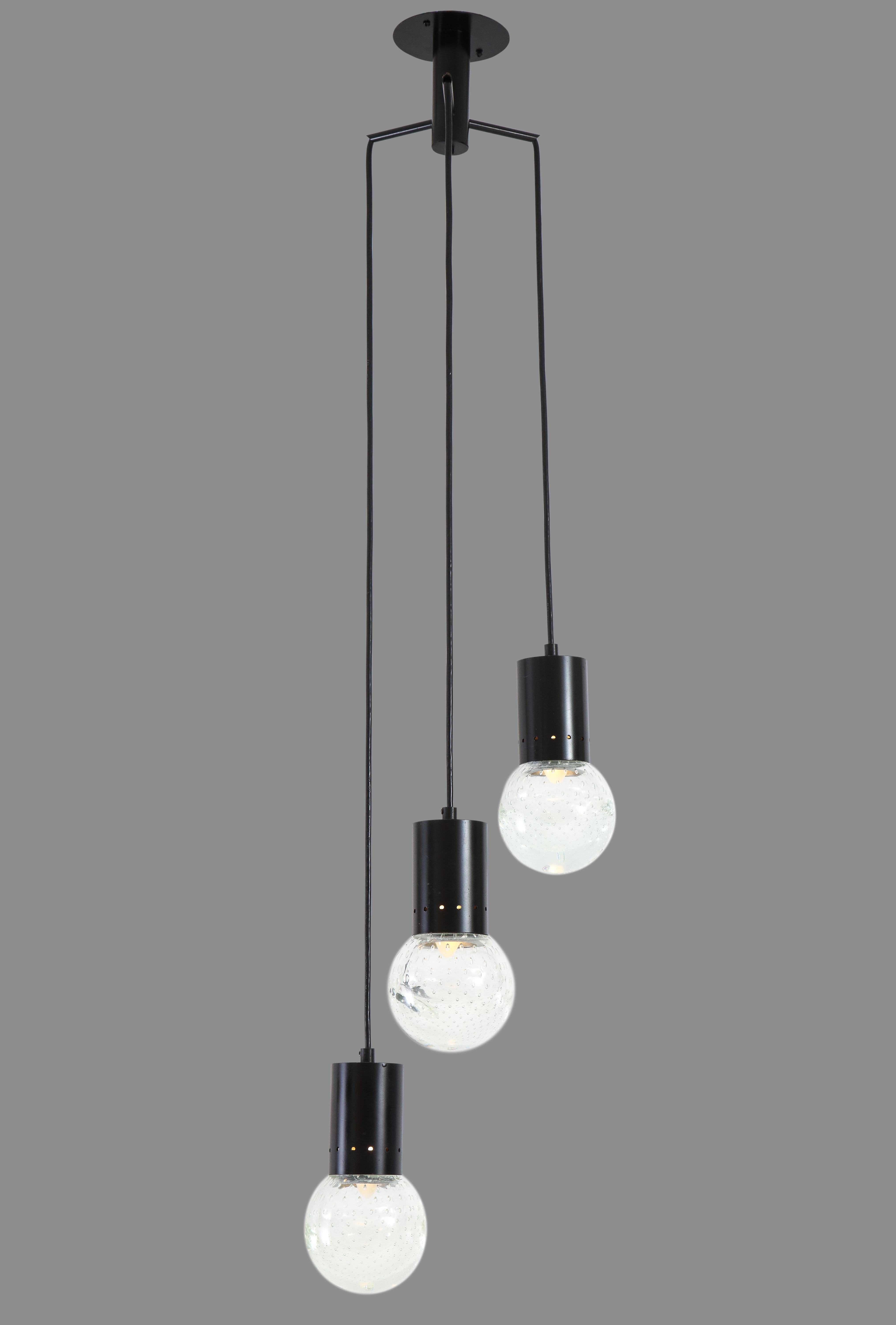 Gino Sarfatti for Arteluce pendant chandelier with three glass globe lights hung on black perforated enameled metal structures suspended from three-arm canopy. The glass globes are by Archemide Seguso using the Bullicante technique involving the