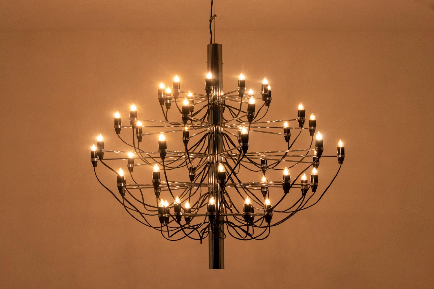 Gino Sarfatti, edited by.
Flos, edited by.

Chandelier with fifty lights arranged in five rows in chromed steel. Structure resting on a rectilinear barrel in black chromed metal. The douiles and the thread become a decoration in