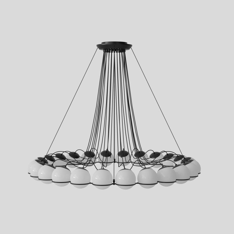 Model 2109
Design by Gino Sarfatti
The Le Sfere chandelier is composed of a circular array of blown opaline glass spheres. Each sphere is held in place by a large black or Champagne painted aluminium ring-structure. Each ring has a small cut,