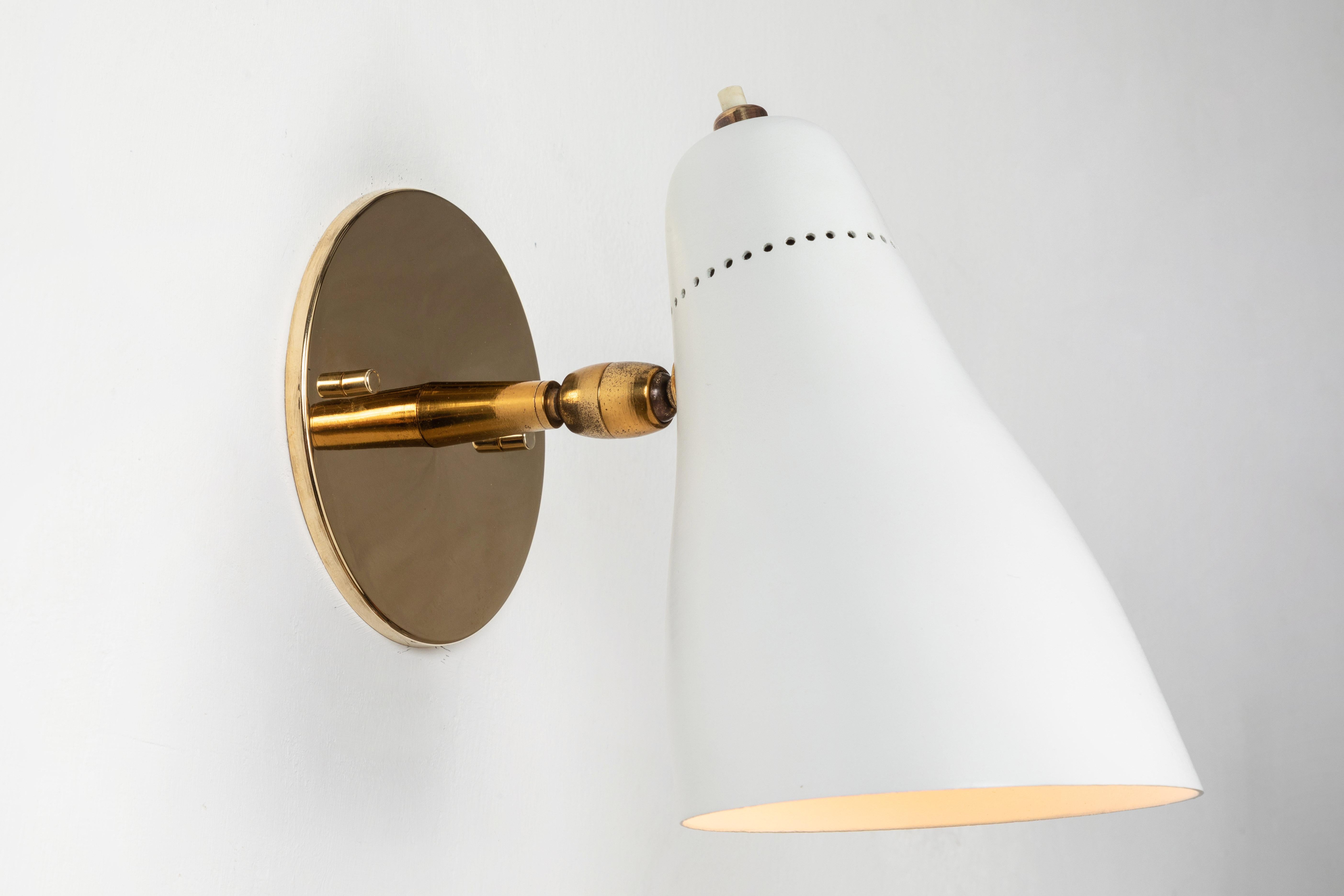Gino Sarfatti Perforated cone sconce for Arteluce, circa 1950. Executed in white painted aluminum and brass. Ball jointed arm connection to shade allows for flexible shade adjustments and multiple configurations. The simplicity of Sarfatti's design