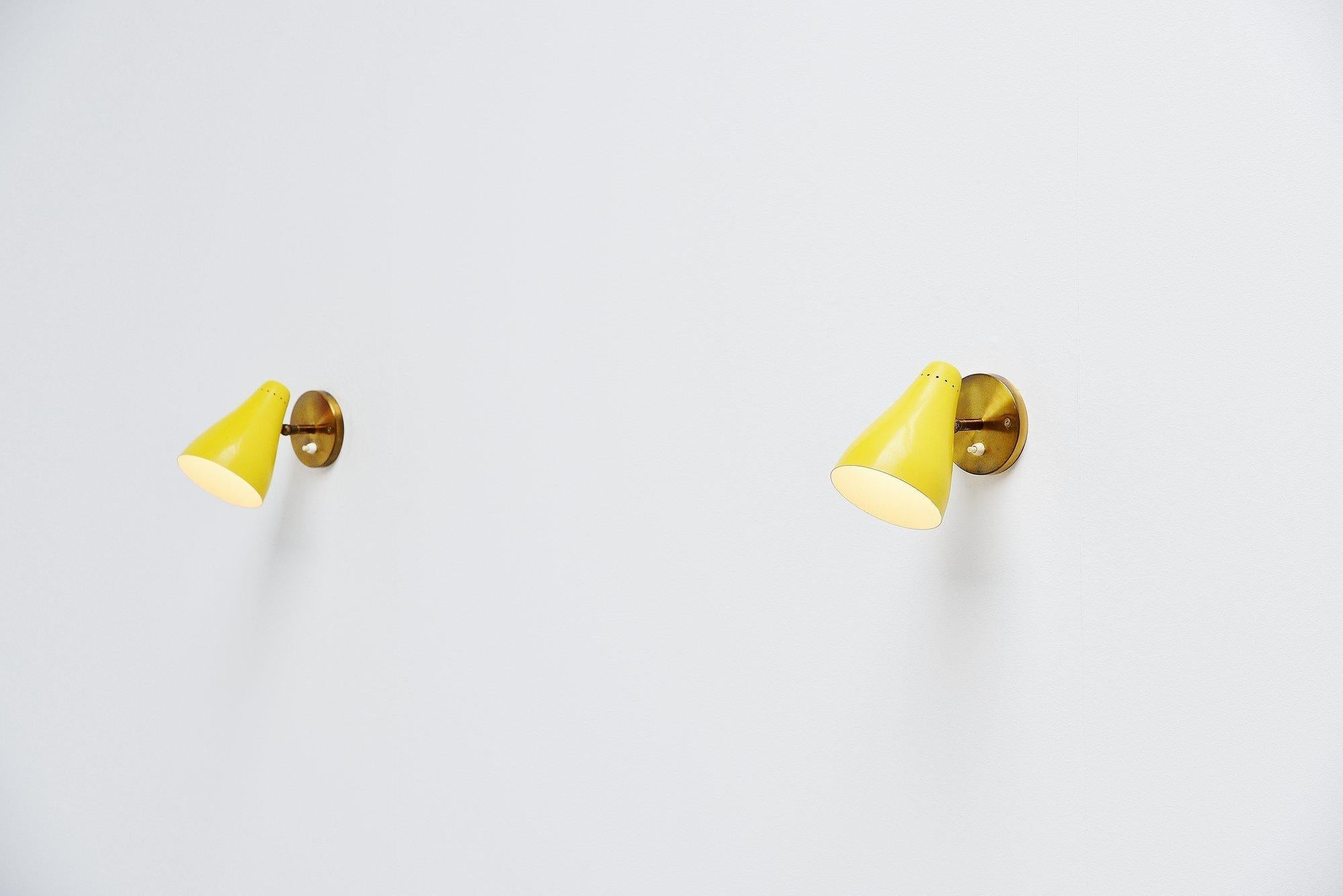 Early pair of sconces model 16c designed by Gino Sarfatti, manufactured by Arteluce, Italy 1948-1950. This early wall lamps have brass wall plates and yellow painted shades with die cut dot pattern at the top of the shade. The lamps are unmarked but