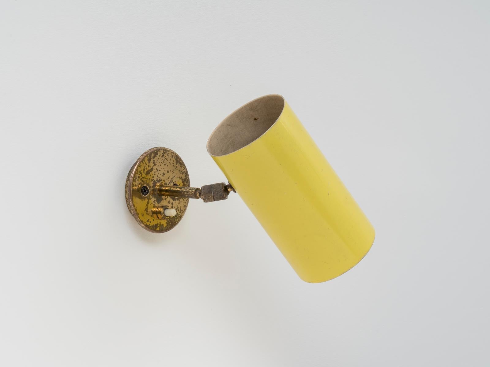 This fully directable wall light was designed by Italian lighting master Gino Sarfatti for his own company Arteluce in the 1950s. This model was mostly manufactured in black or cream white color, this yellow version is rarer. The lamp is left in its