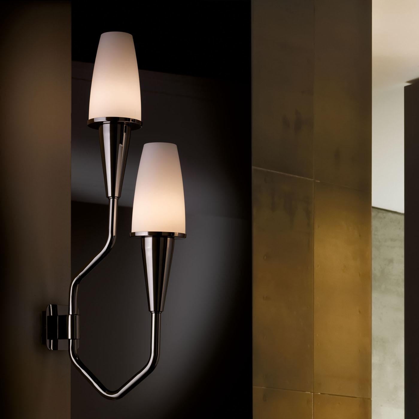 A deluxe design with bracket, base and arms in polished nickel brass, the Gio Applique Wall Lamp exemplifies pure elegance. A beautiful addition to any stylish decor, the lamp features two diffusers in white acid-etched glass.\nBulbs: 2 x max 40W G9