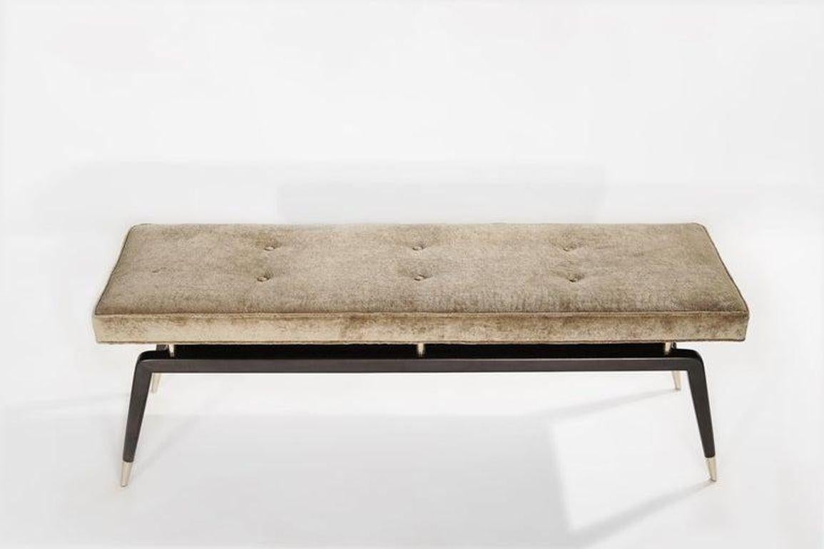Discover The Gio Bench by Stamford Modern: Inspired by the iconic Gio Ponti, this bench seamlessly marries classic elegance with modern functionality. Its distinctive angled legs, adorned with metal sabots and risers, support a sumptuous upholstered