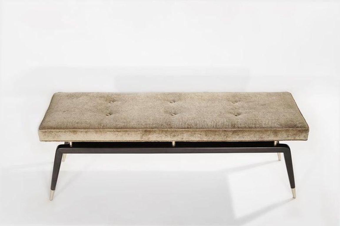 The Gio Bench by Stamford Modern: a perfect blend of Gio Ponti's timeless design and modern functionality. This elegant bench features signature angled legs with metal sabots for added stability and longevity. The upholstered cushion, elevated by