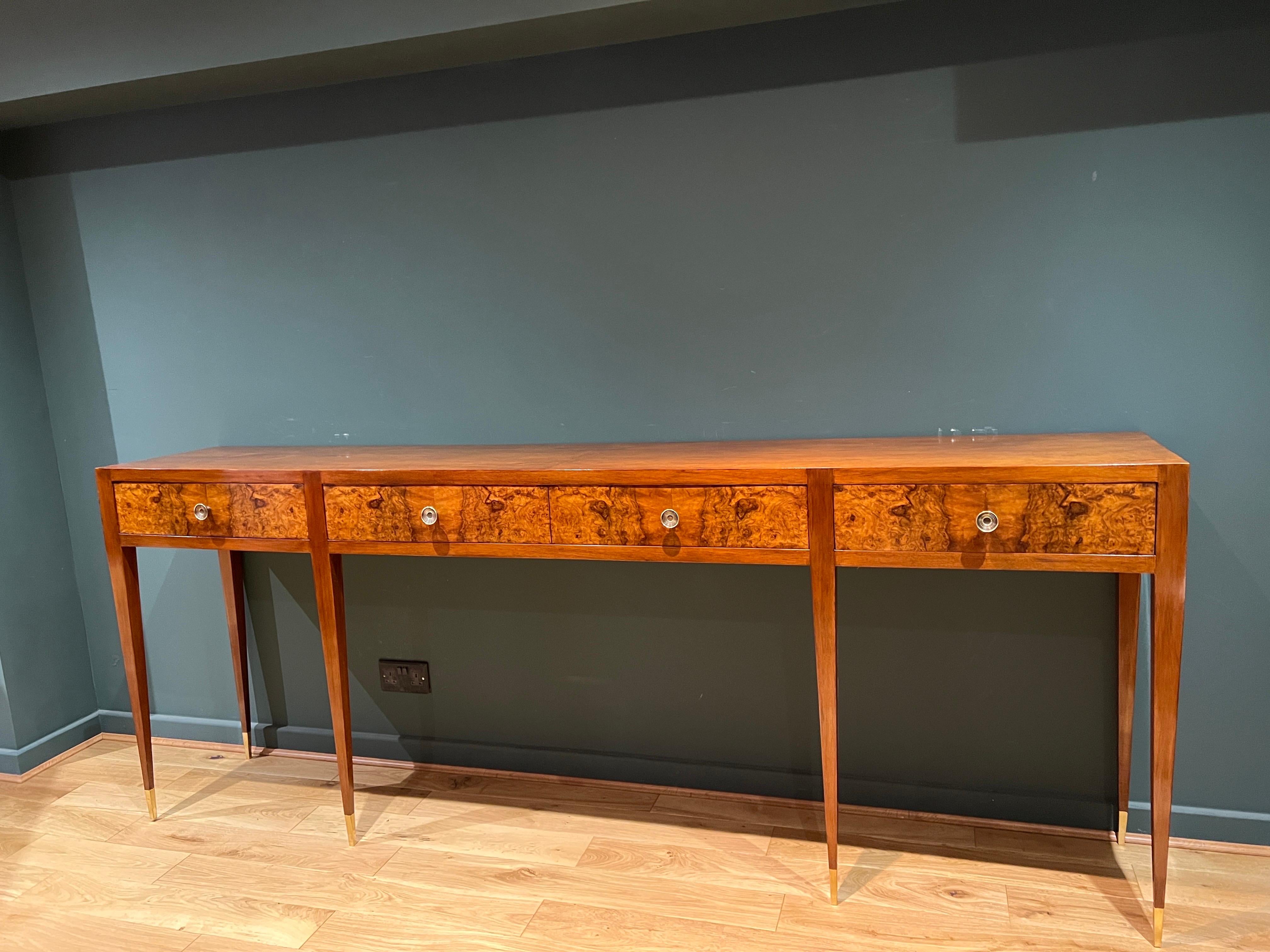 A beautifully crafted large console table in cherrywood with four drawers in contrasting burl walnut and brass handles . The console stands on four legs to the front and two to the back all with brass sabots. 
This piece was acquired by our client