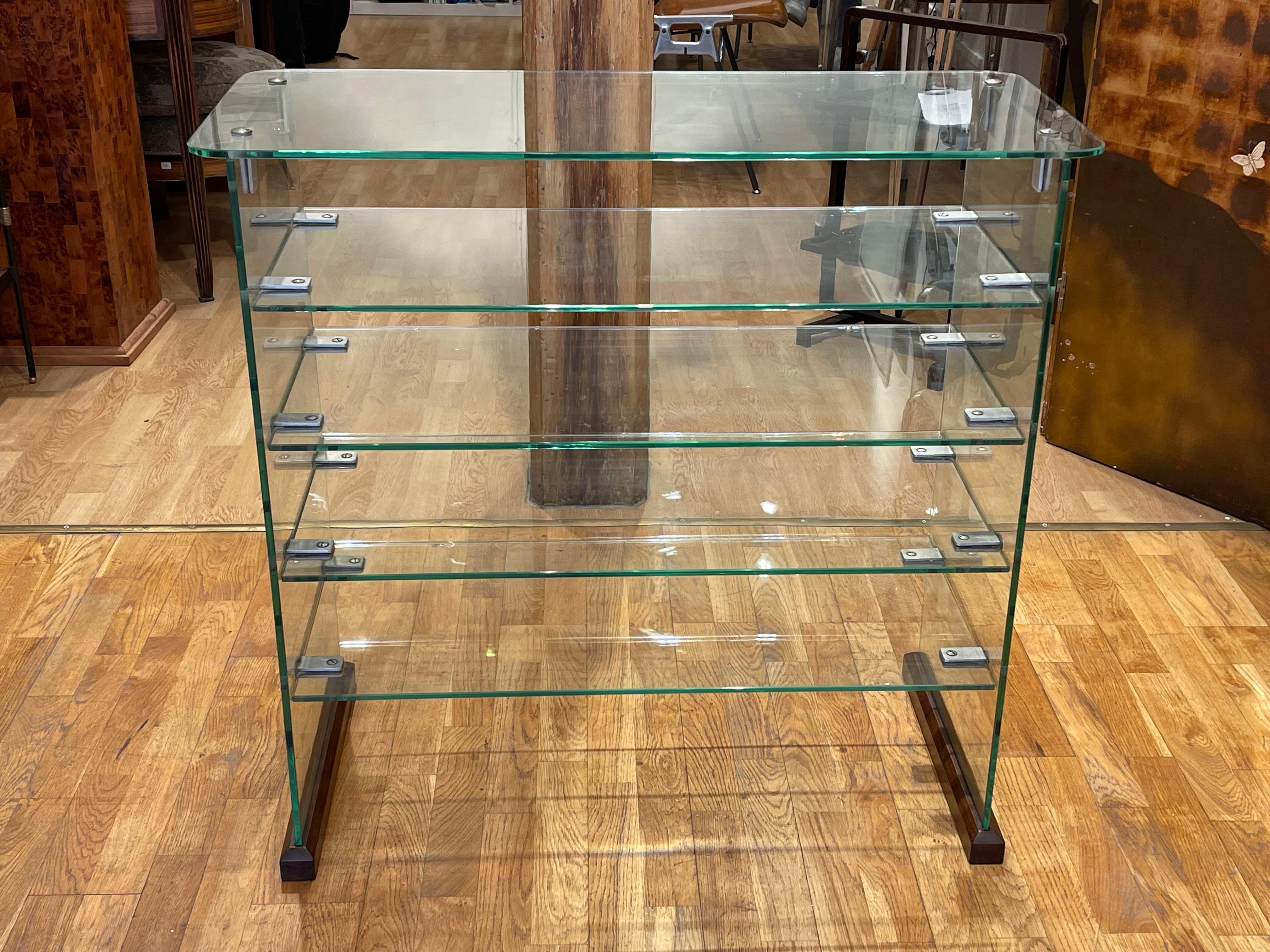 Excepptionnal brass and glass shelf, featuring five supported wooden shelves held by two glass blades at the ends, all securely connected and fixed by brass screws.

The glass is engraved «Vitrex»

Originally designed for the Ventrocoke offices in