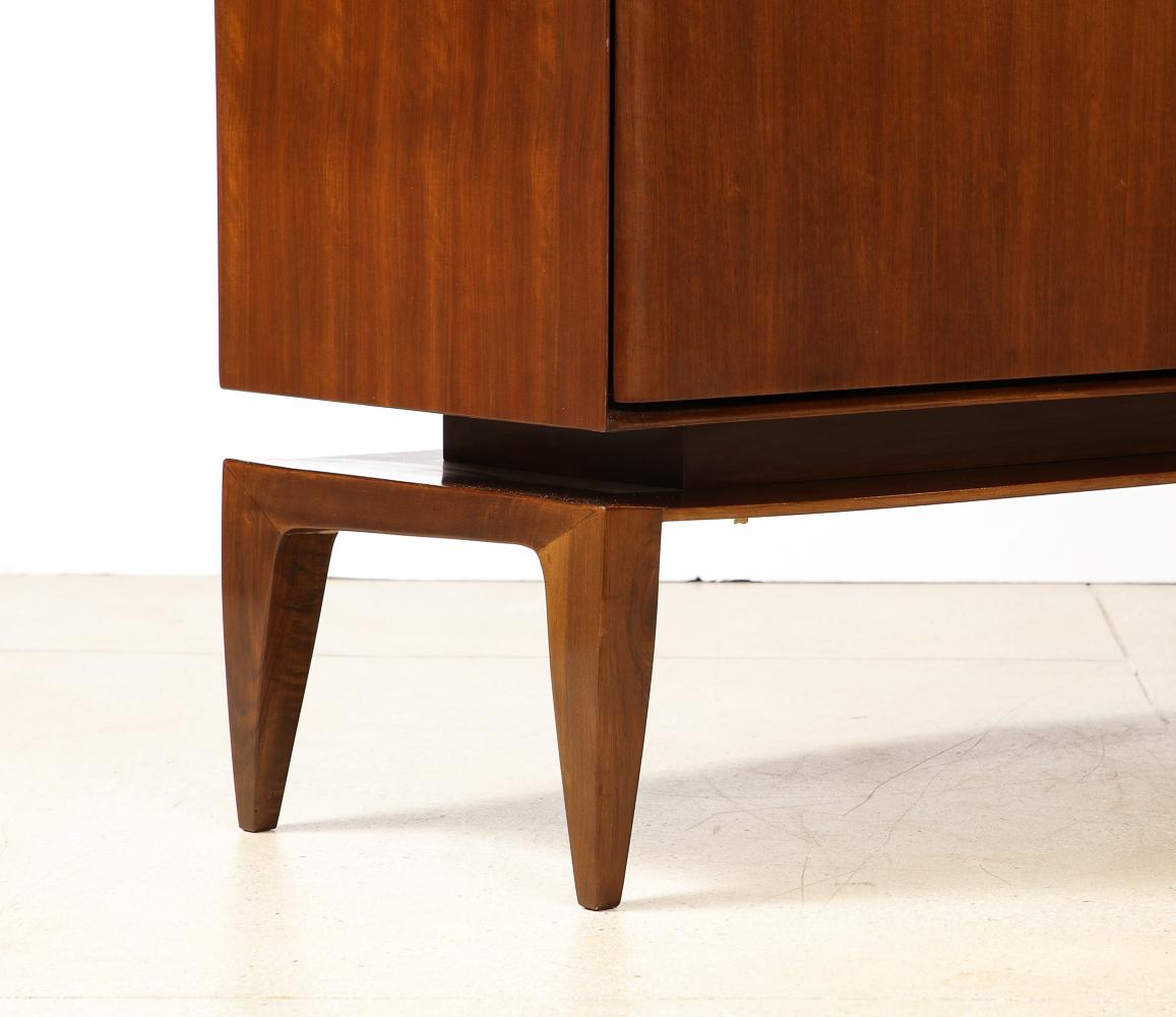Rare three-door floating cabinet by Gio Ponti for M. Singer & Sons.
Mahogany cabinet raised on tapering legs. Three knife-edge doors set into a bevelled frame. Interior drawers and open shelves. This cabinet was studio-made in Italy and marketed