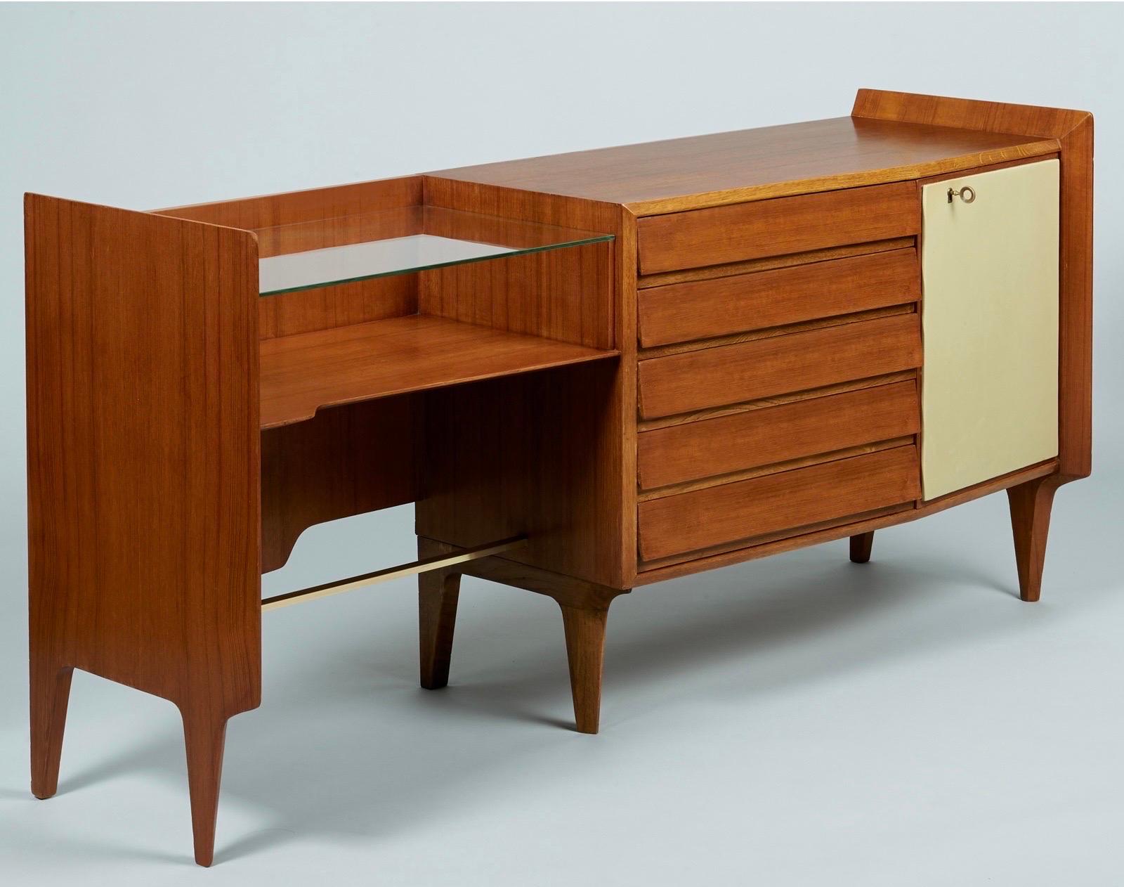 Gio Ponti (1891 - 1979) 

An exceptional and rare asymmetrical credenza by modernist master Gio Ponti, in mahogany with five drawers angled subtly outwards, a glass writing desk, polished brass hardware, and the original cream-colored skai door with