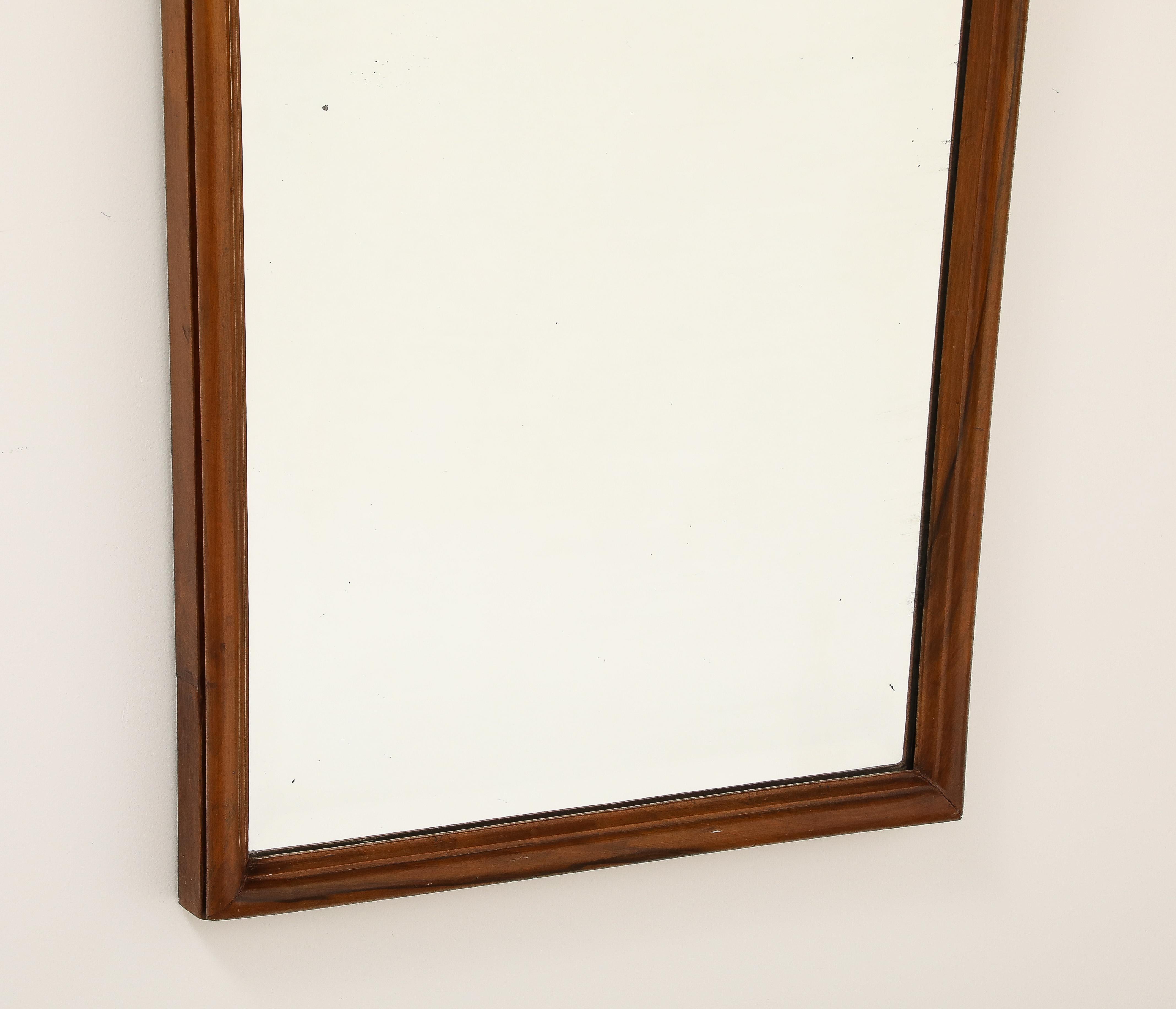 Ein sehr schöner handgeschnitzter Spiegel mit Nussbaumrahmen, der Gio Ponti zugeschrieben wird, um 1930.  Die dicke, abgeschrägte Glasplatte ist der Form des Nussbaumrahmens nachempfunden, mit dekorativem, gestuftem Schnitzwerk am Scheitel und