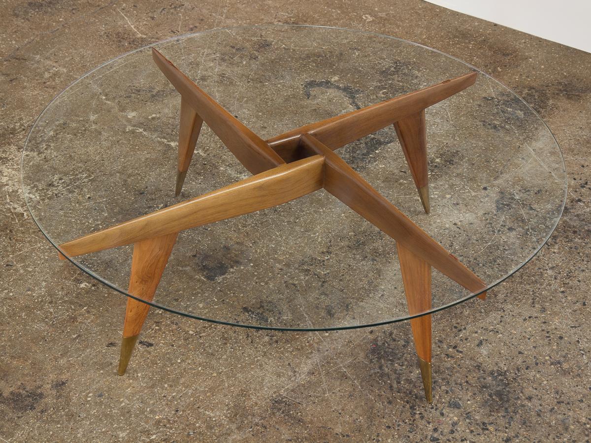 Important and rare Gio Ponti for M. Singer & Sons cocktail table Model 1101. Elegant, angular form is carved from exquisite Italian walnut. Smooth tempered glass surface lends a light, transparent quality to the design. Pointed brass sabots at the