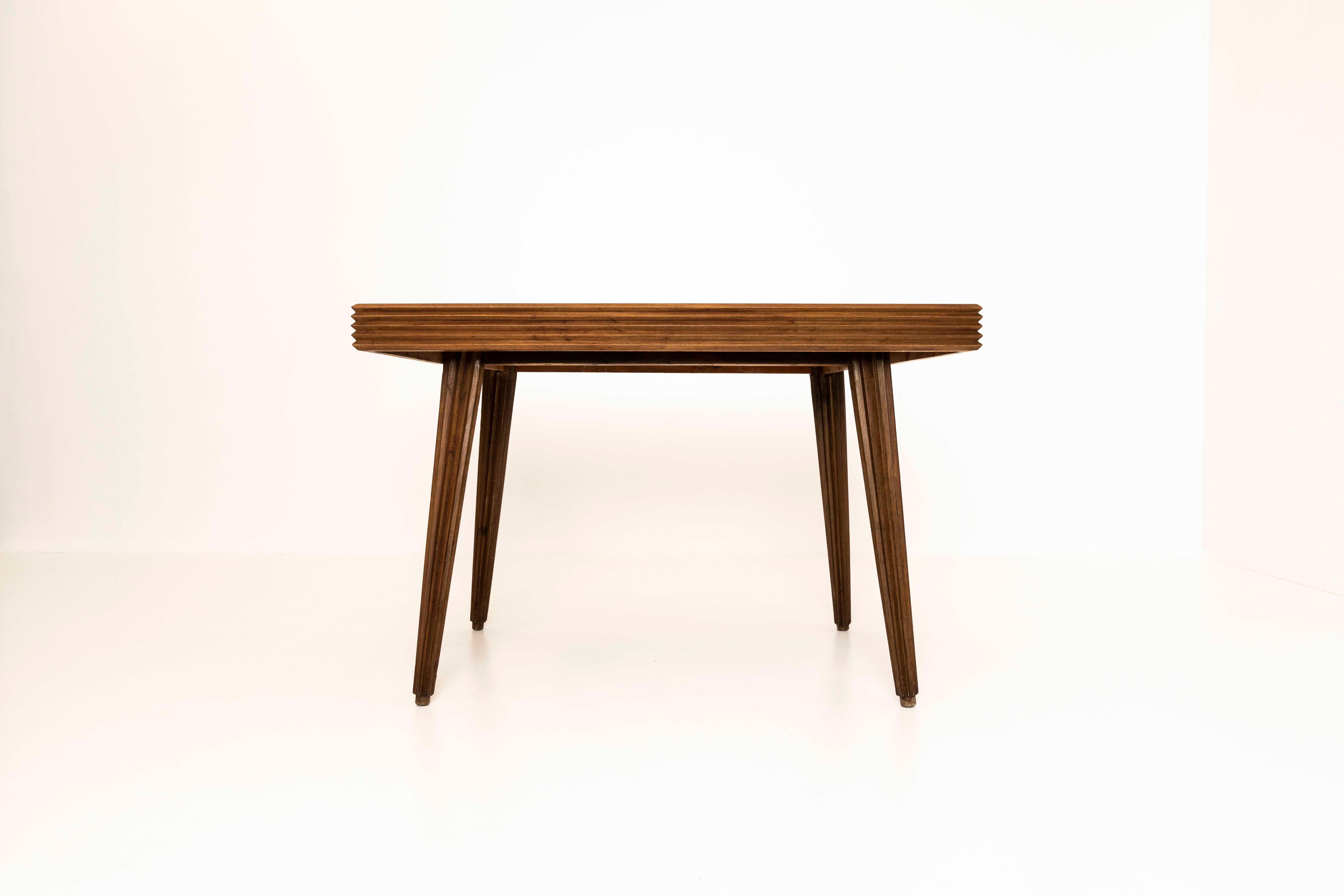 Amazing dining table by Gio Ponti from the early 1940s, Italy. It has a rectangular top in veneered Italian walnut with underneath four tapered fluted legs. A similar striking fluted, grooved pattern can also be found in the edges of the table. It