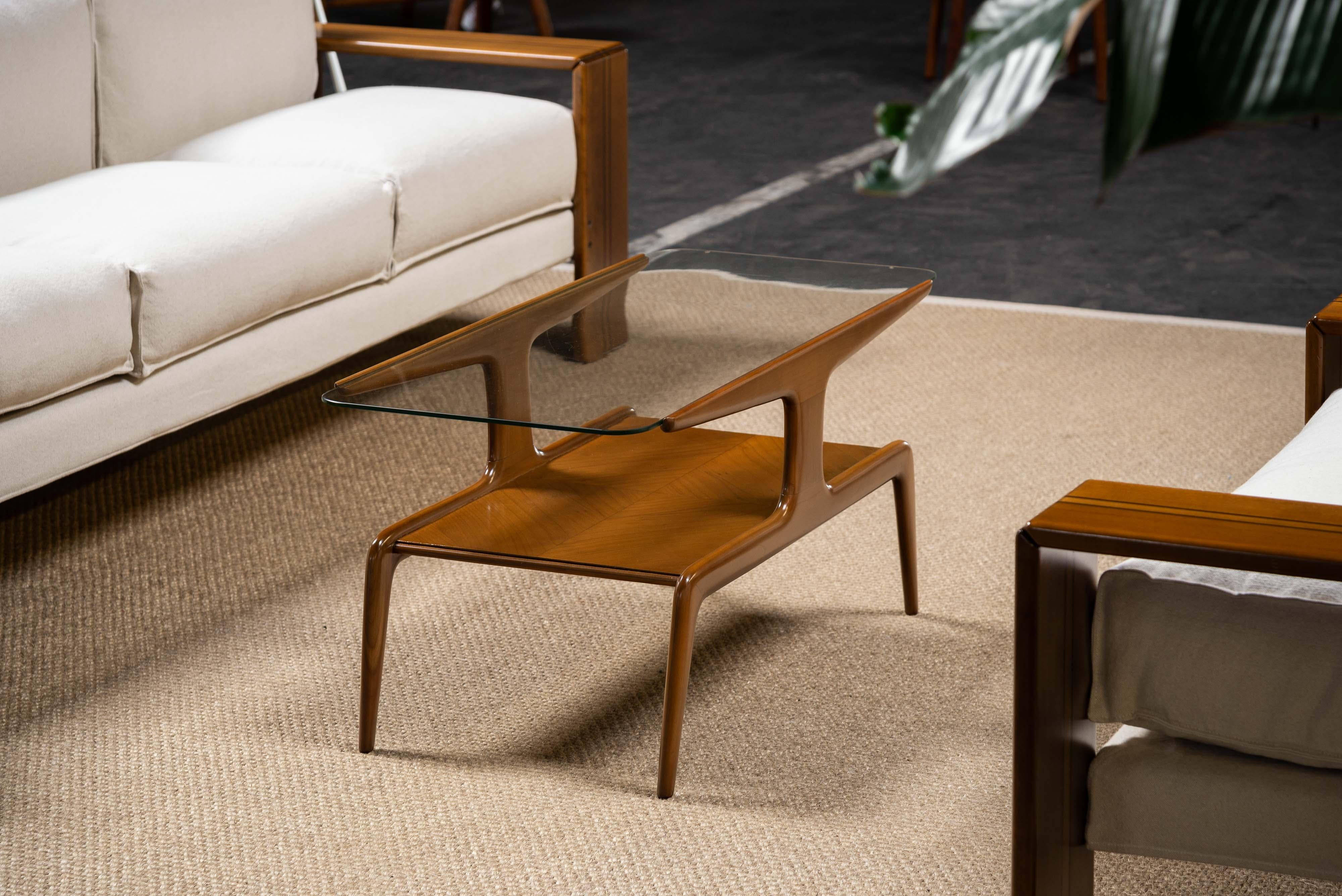 Iconic coffee table by one of the most important Italian architects of all times, Gio Ponti. A solid caramel walnut table crafted by Domus Nova. It's got that classy Gio Ponti shape with on top a sleek glass surface. A beautiful feature is the