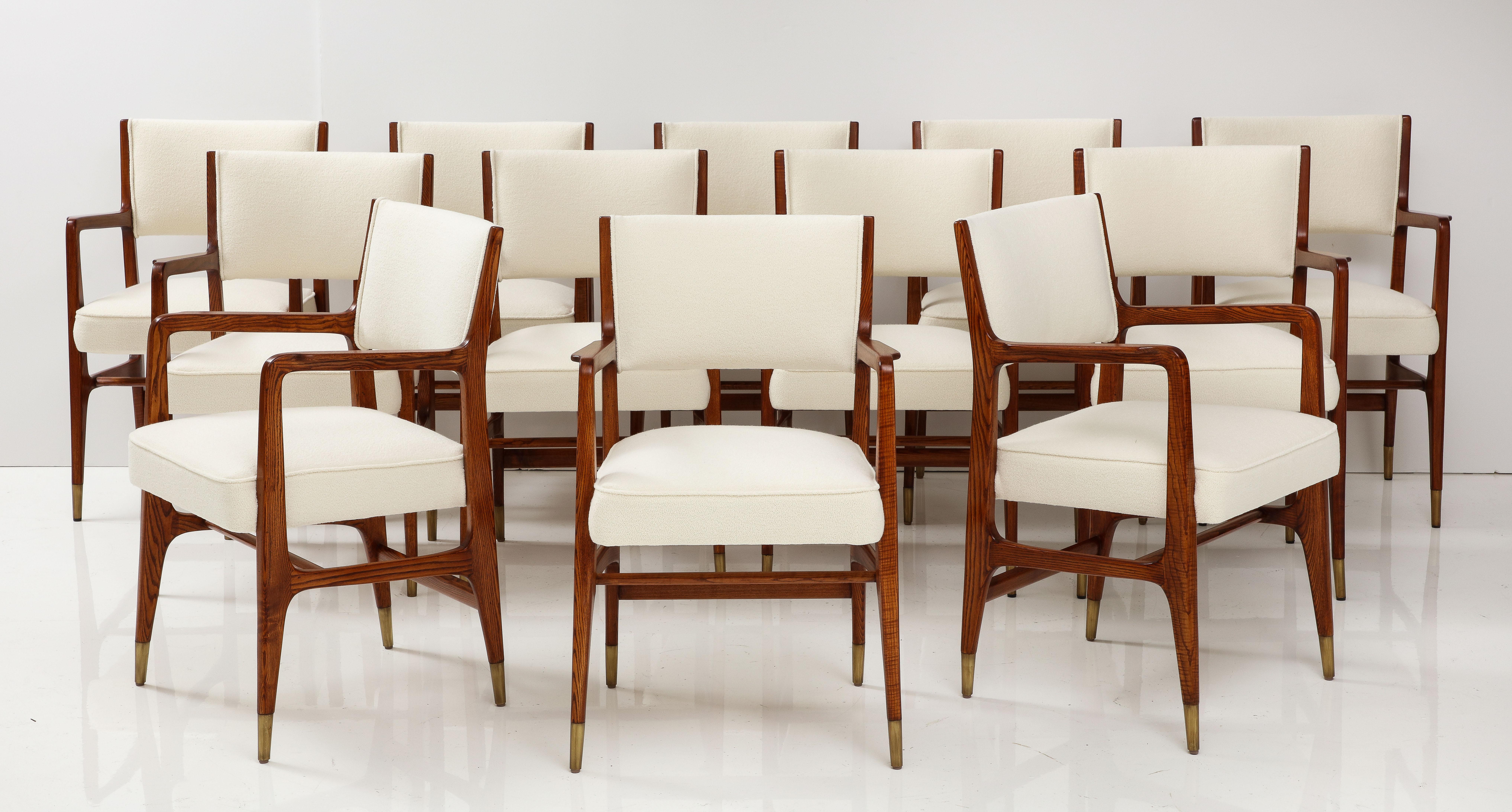 Gio Ponti for Cassina rare matched set of 12 dining chairs model 110 with oak frames, upholstered seat and back in ivory bouclé, and ending in brass sabots, Italy, 1950s.  These Ponti classic architectural armchairs have sculptural curved armrests,