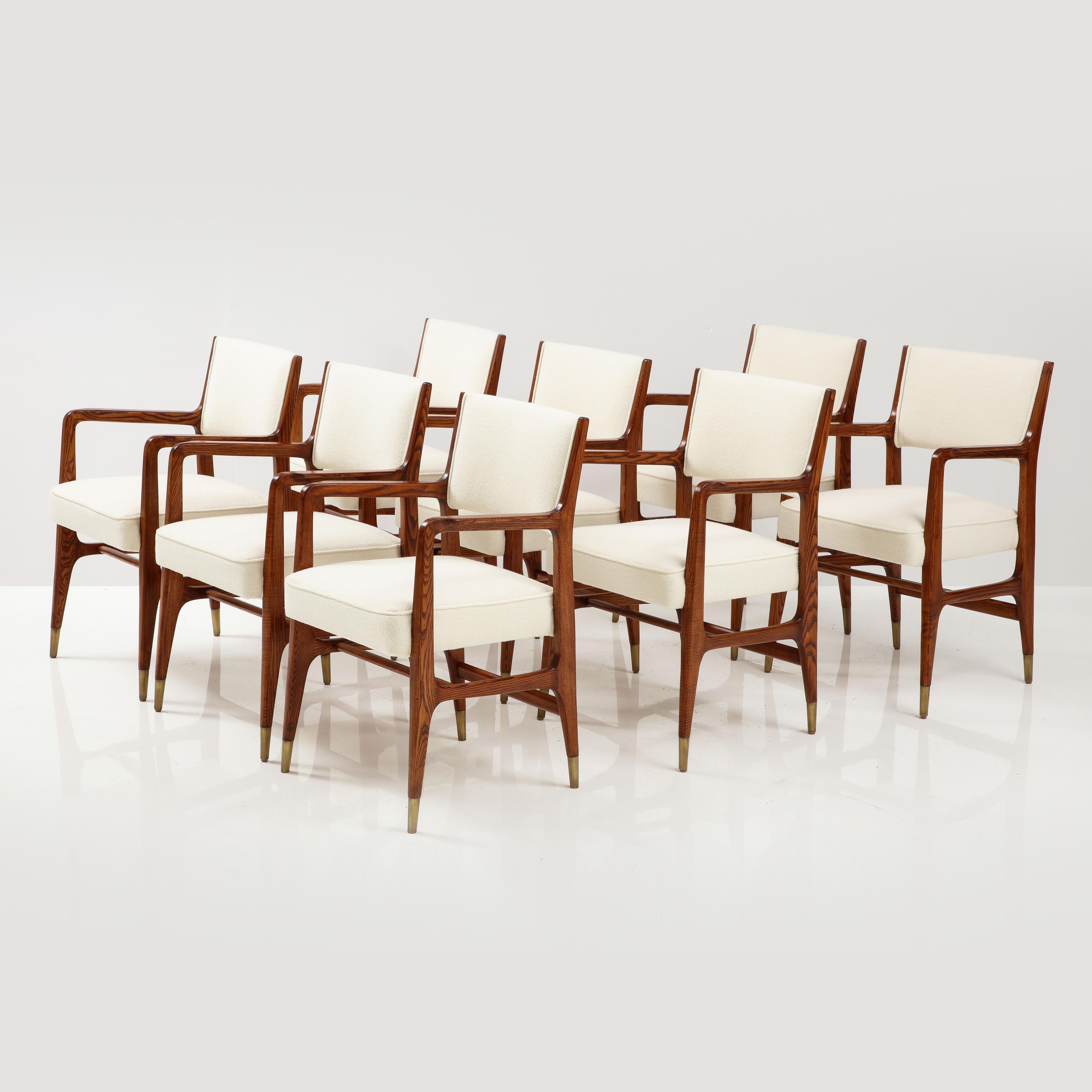 Gio Ponti for Cassina rare set of 8 dining chairs model 110 with red oak frames, upholstered seat and back in ivory bouclé, and ending in brass sabots, Italy, 1950s. These Ponti classic architectural armchairs have sculptural curved armrests,