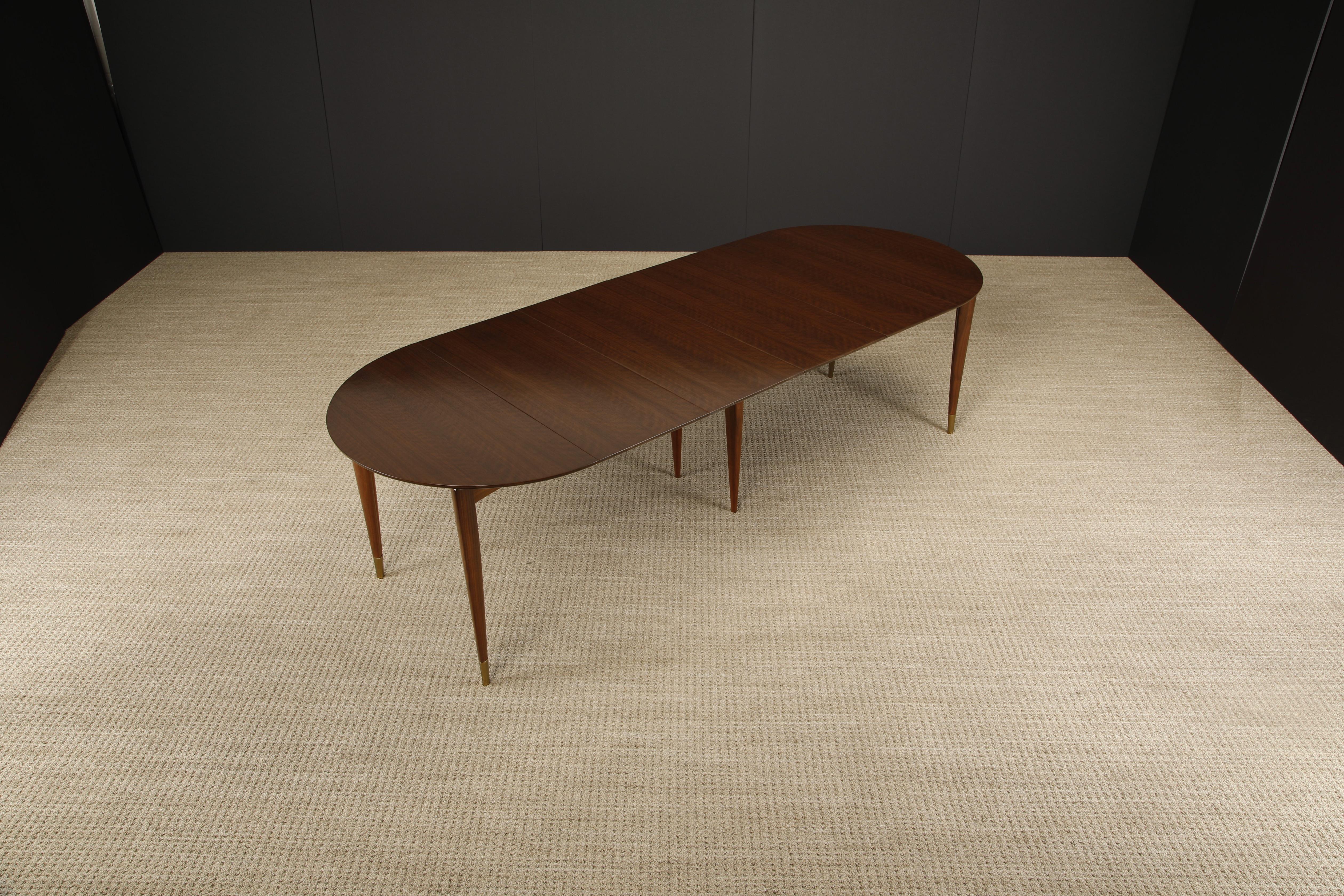 This restored Model 2135 extendable dining table with four leaves by Gio Ponti for Singer & Sons features gorgeously veined Italian Walnut with sculpted legs to Gio Ponti's signature form, capped with brass sabots. 

Documented in the Singer & Sons,