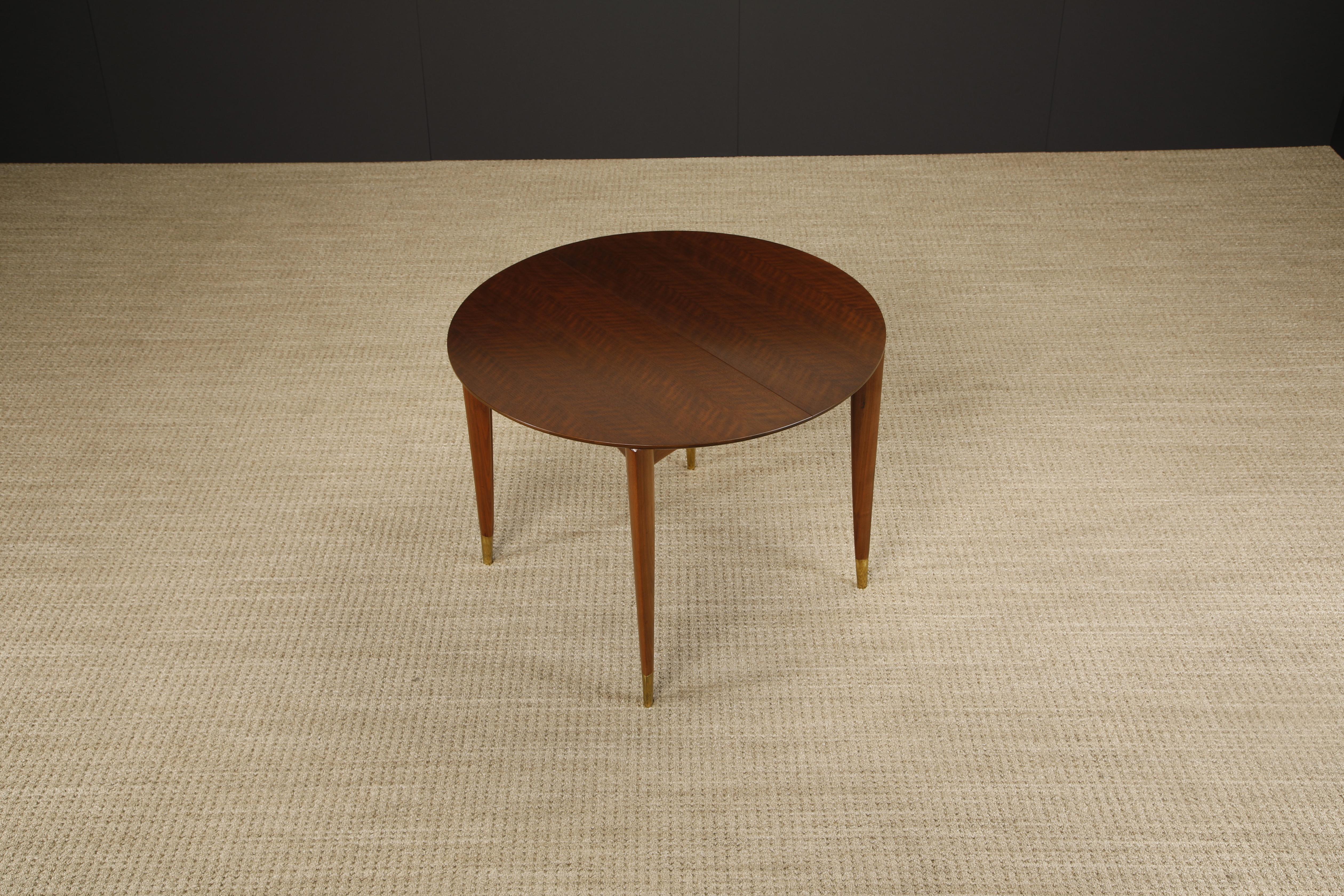 This restored Model 2135 extendable dining table with four leaves by Gio Ponti for Singer & Sons features gorgeously veined Italian Walnut with sculpted legs to Gio Ponti's signature form, capped with brass sabots. Signed with original 'M. Singer &