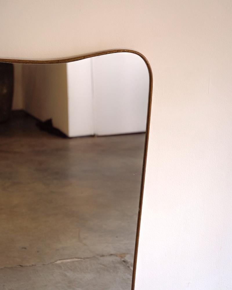 Large brass wall mirror with curved detailing by Gio Ponti and manufactured by Fontana Arte. Brass is nicely patinaed. 

Top width - 23.5