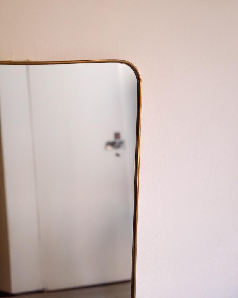 Large brass wall mirror with curved detailing by Gio Ponti and manufactured by Fontana Arte. Brass is nicely patinaed. 

Top width - 21