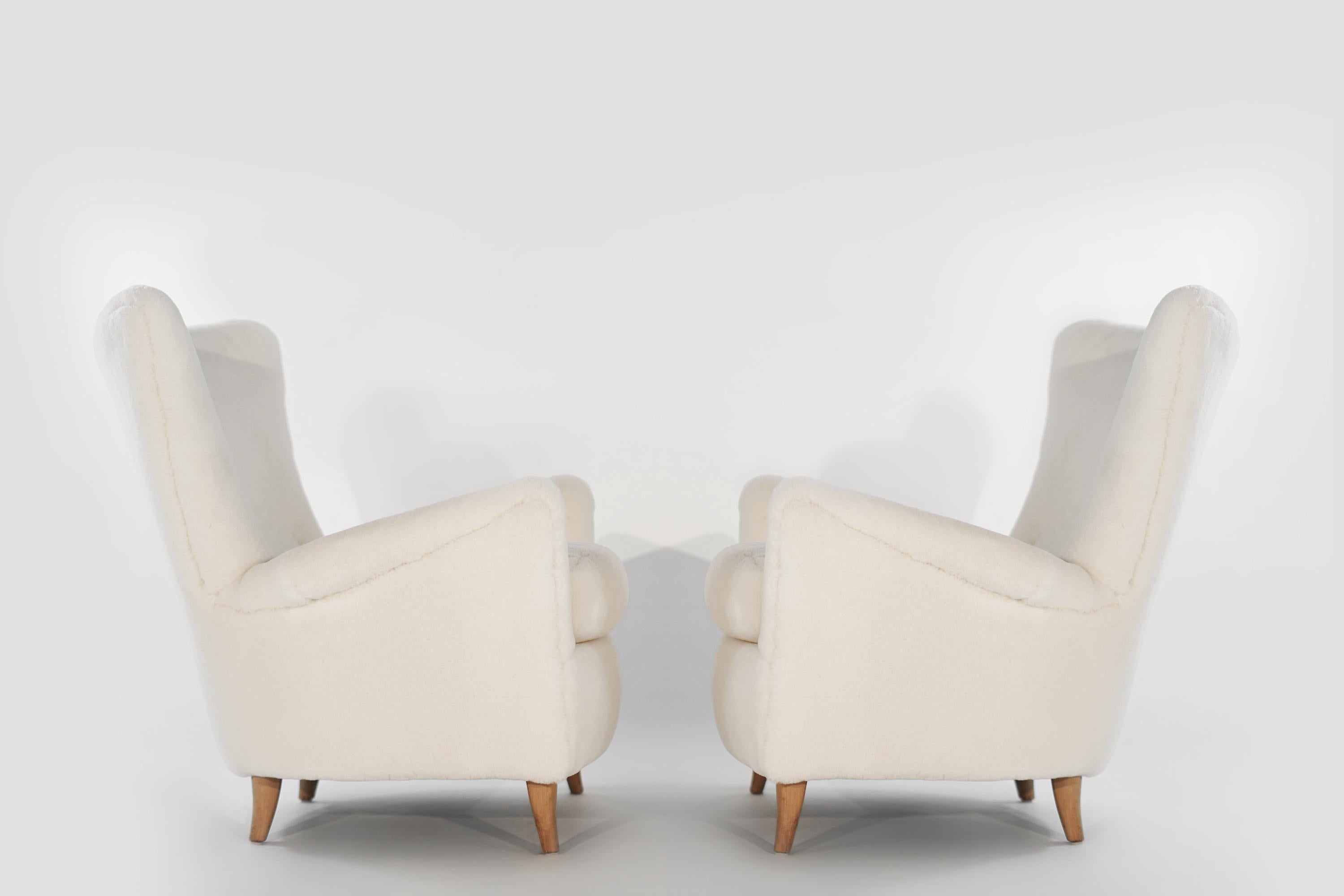 Pair of lounge chairs attributed to Gio Ponti designed for the Hotel Bristol in Merano, Italy, circa 1950s. Completely restored down to their frames, re-upholstered in Great Plains Shearling by Holly Hunt. 
Maple legs in original vintage