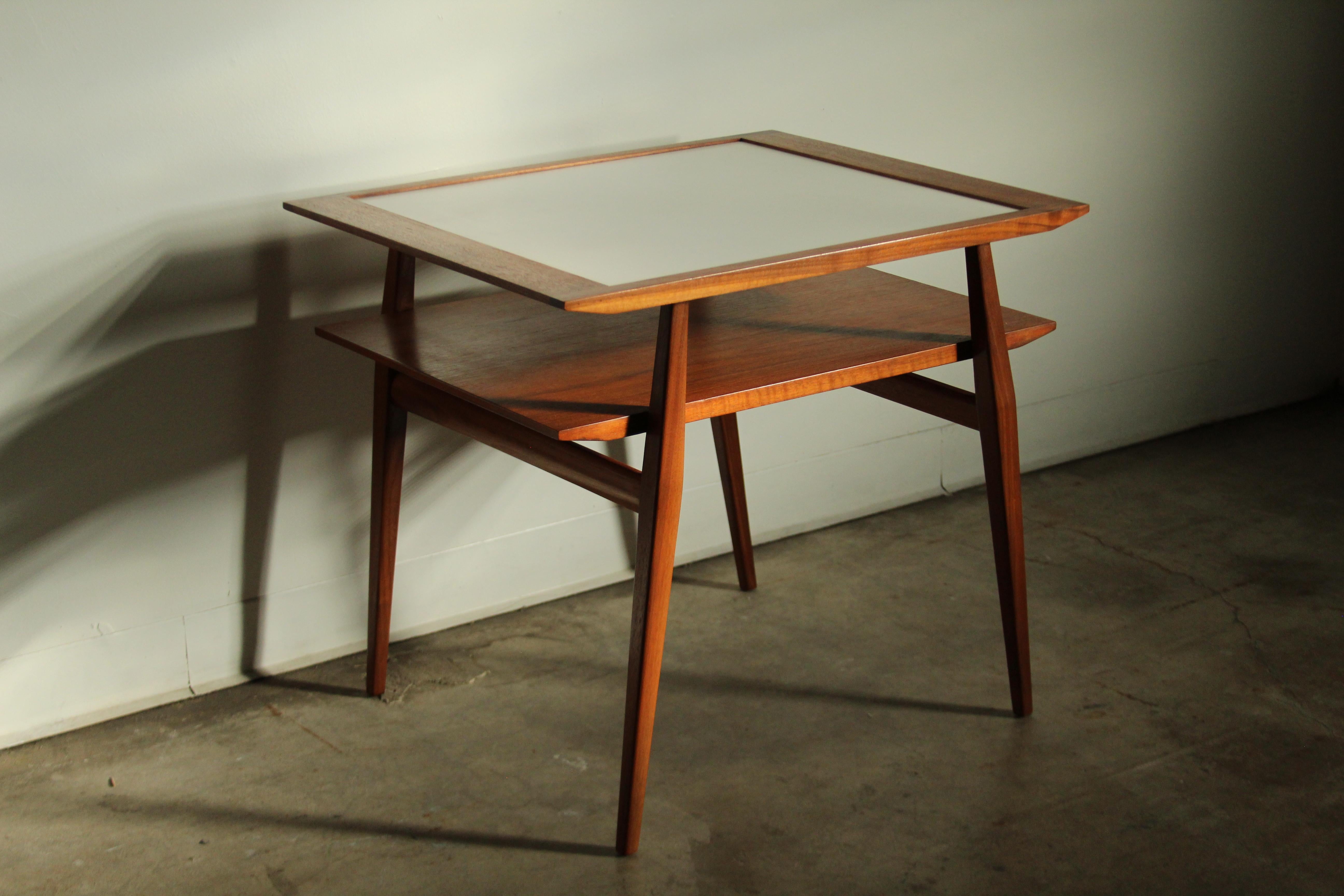 A stunning, sculptural accent table, Model 2146, designed by Gio Ponti for by M. Singer & Sons, and produced in Italy by Giordano Chiesa in the 1950s. The table features a sculpted solid walnut two-tier frame with an inset formica top. It is
