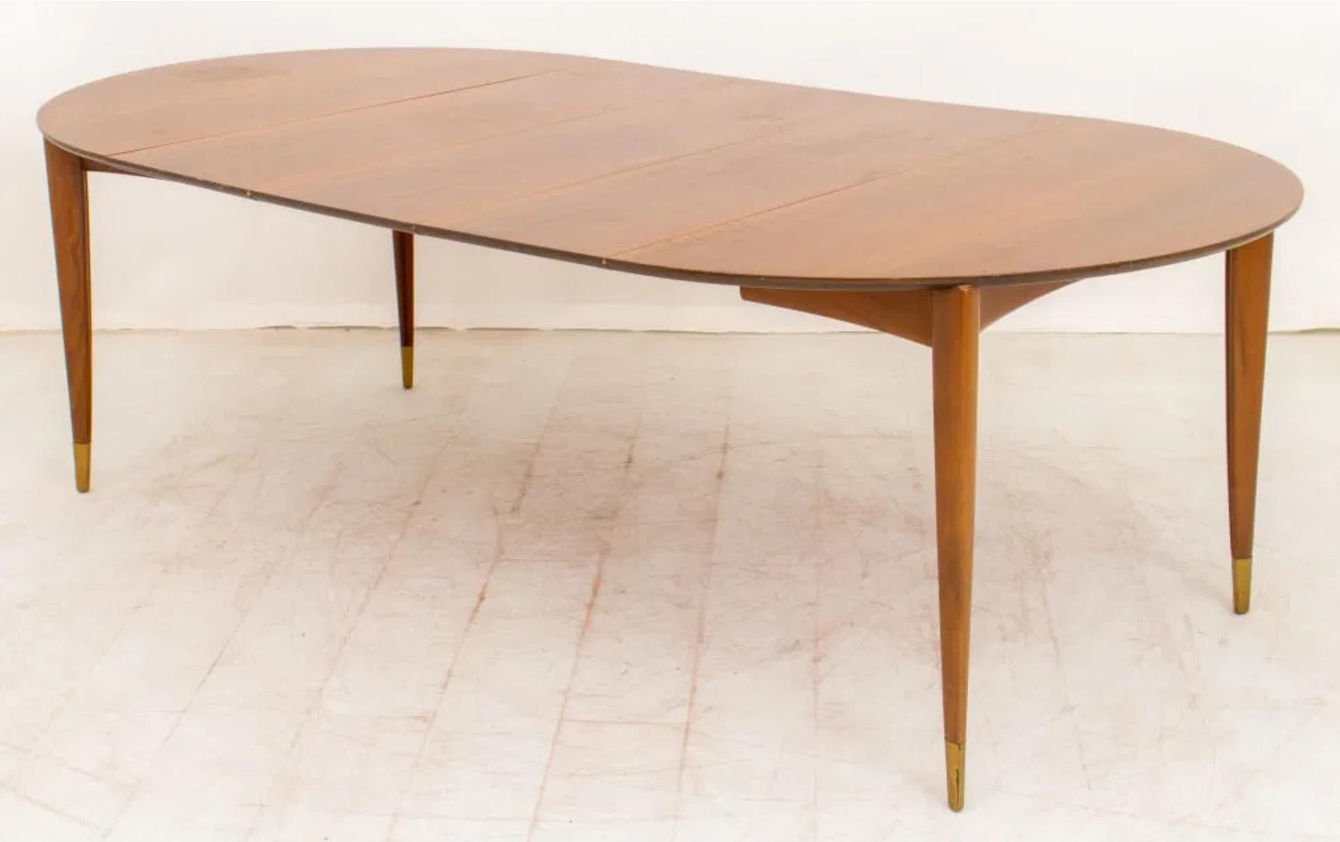 Classic Gio Ponti extension dining table in a wonderful dappled Italian walnut veneer.   The round top with sharp edge floats on sculpted tapering legs ending in brass sabot. With three 14” leaves, the table expands to 90” and comfortably seats 8-10