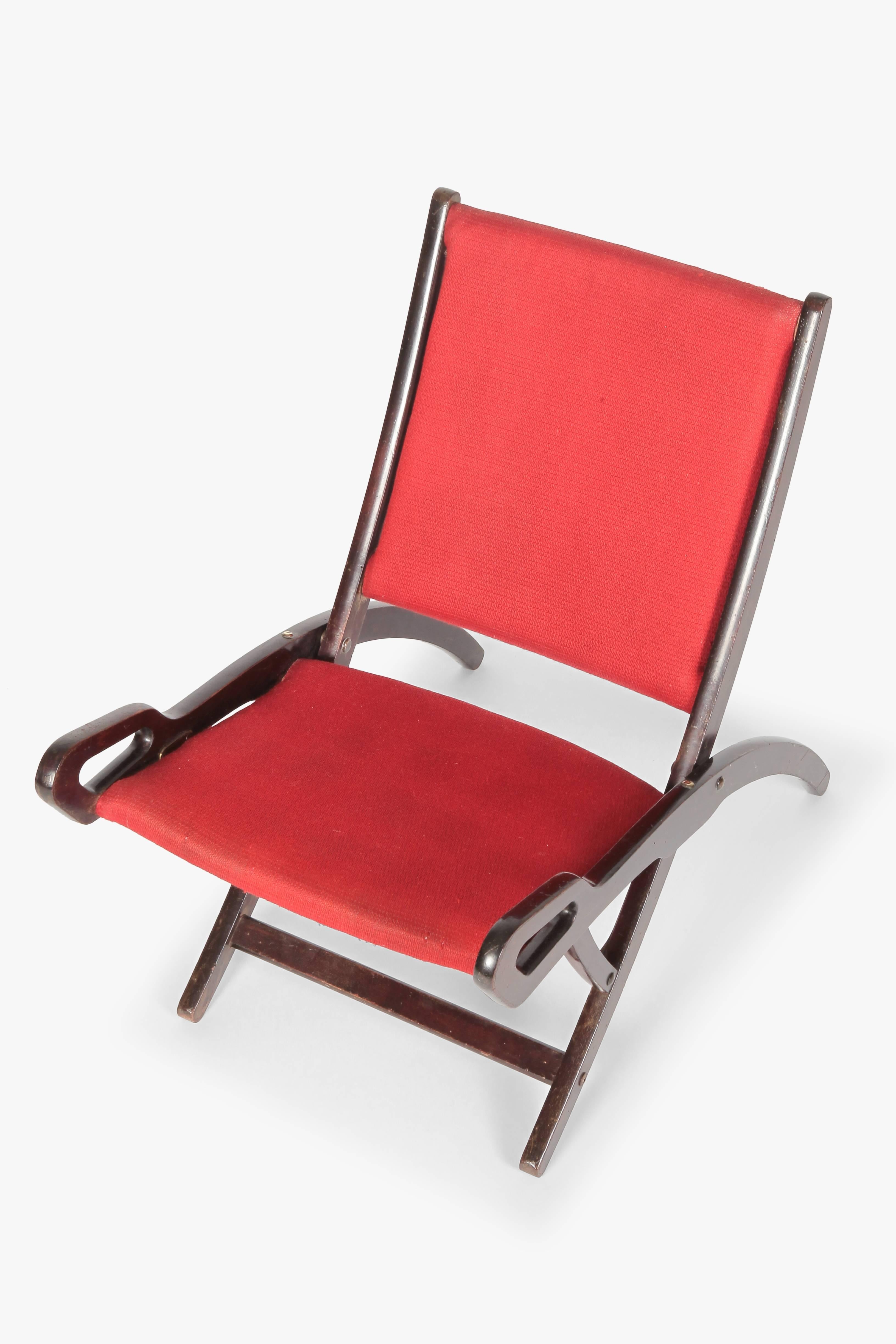 Gio Ponti “Nifea” folding chair manufactured by Fratelli Reguitti in the 1950s. Dark, lacquered walnut frame with striking patina and brass hardware. Seat and rest are covered with the original red cotton fabric. Beautiful vintage condition.