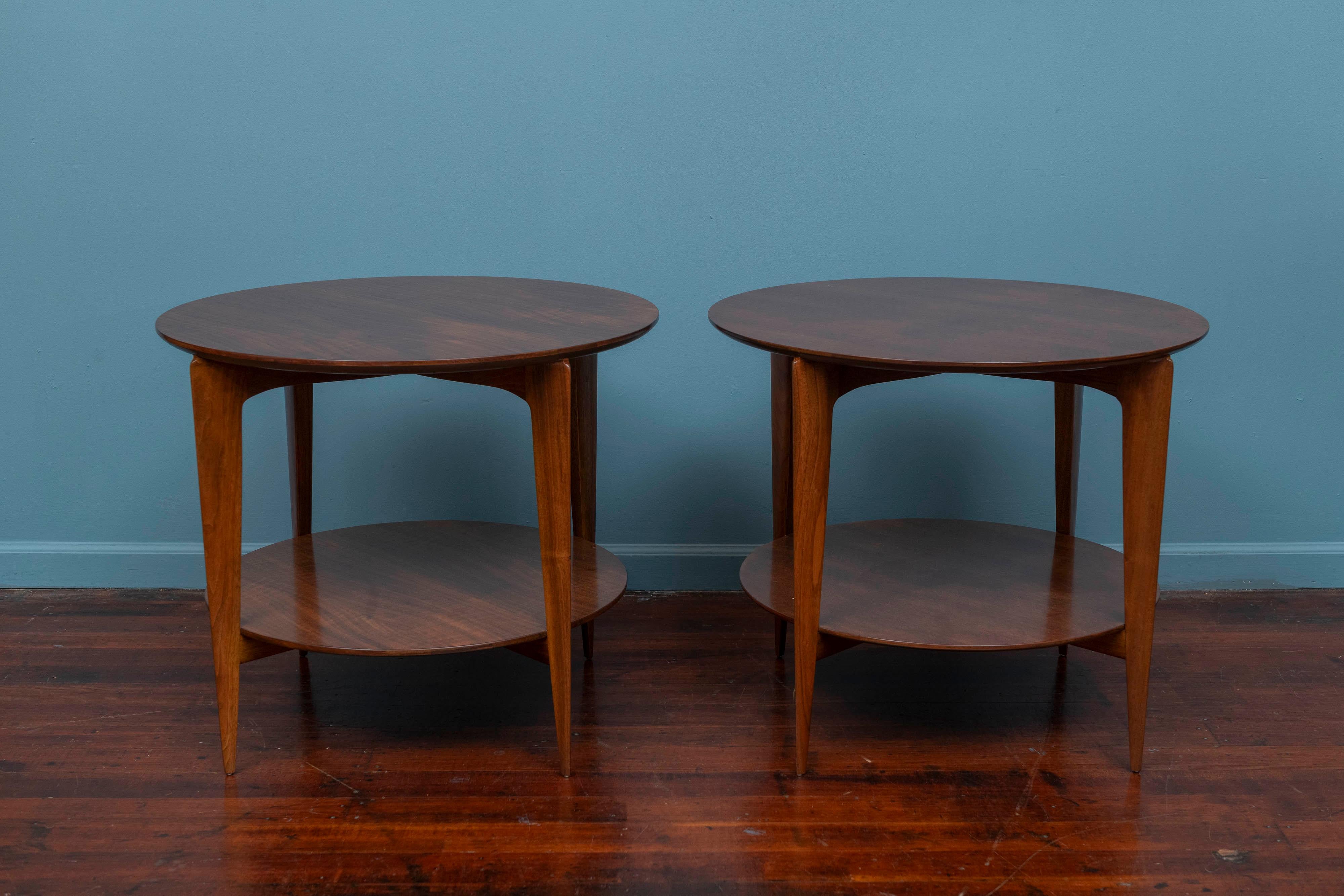 Pair of Gio Ponti design ocassional tables for Singer & Sons, Model 2136. Rare pair of elegant tables by the master of Italian design Gio Ponti. Executed in figured walnut with two tiered round beveled top and shelf on tapering saber legs. Newly