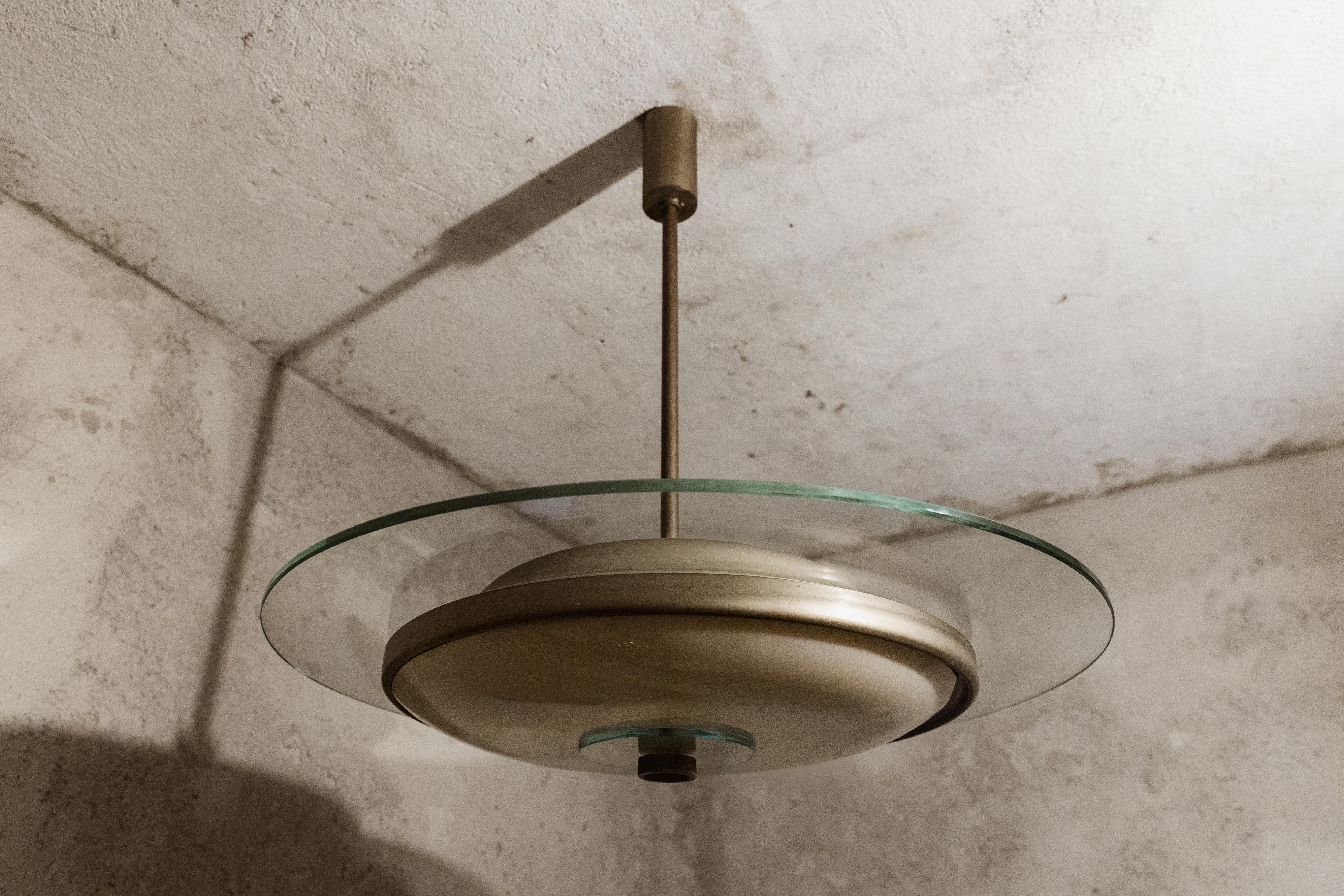 Gio Ponti “Padelle” ceiling light for Fontana Arte, brass and glass, Italy, 1933.

This suspension lamp, manufactured by Fontana Arte, features a transparent glass disc and a brass one, while a chrome-plated brass frame supports the structure. This