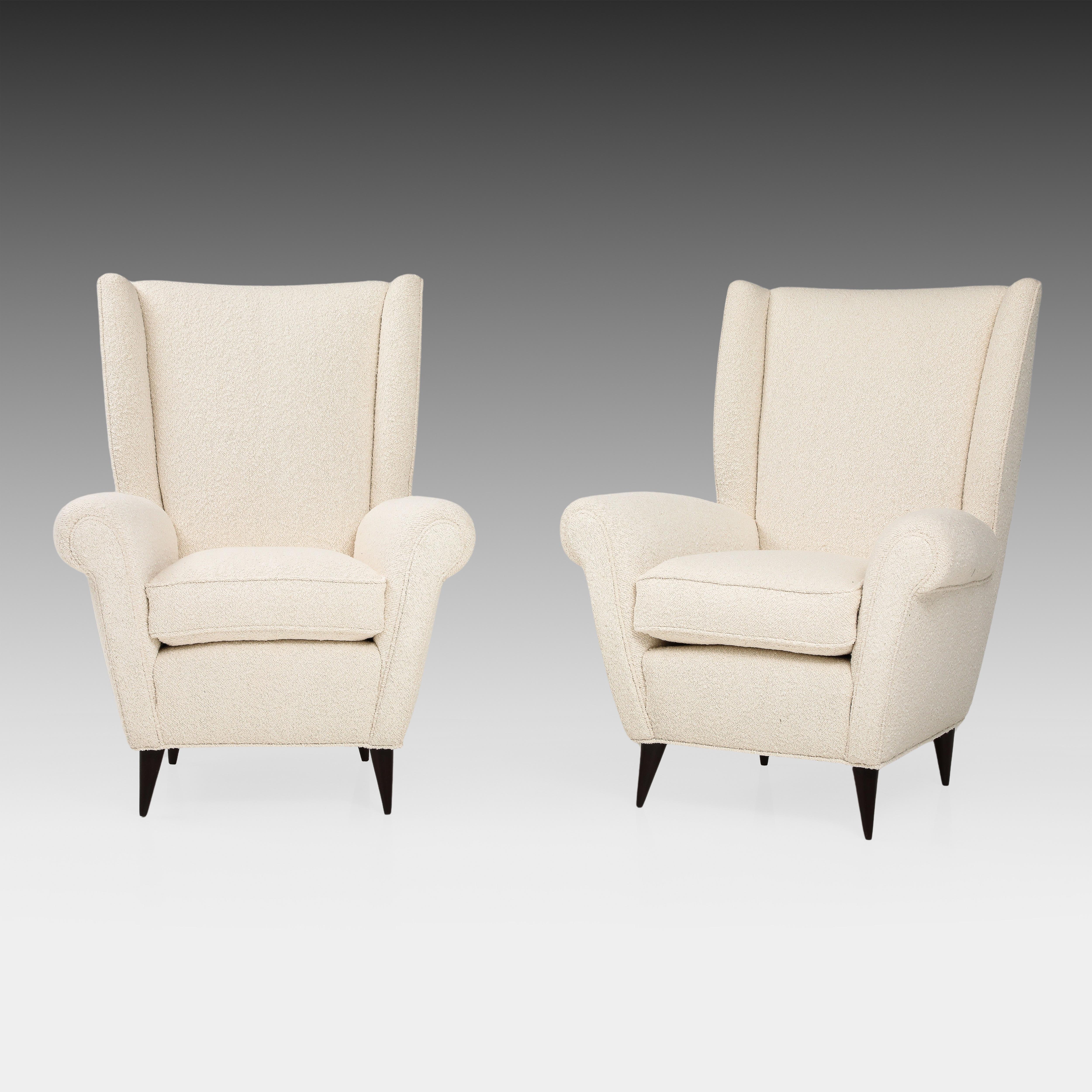 Gio Ponti pair of high back armchairs or lounge chairs in white or ivory bouclé with polished walnut tapering legs.  These chic armchairs have the classic shape of a wingback chair, but with the modernist lines and sculptural expression exemplary of